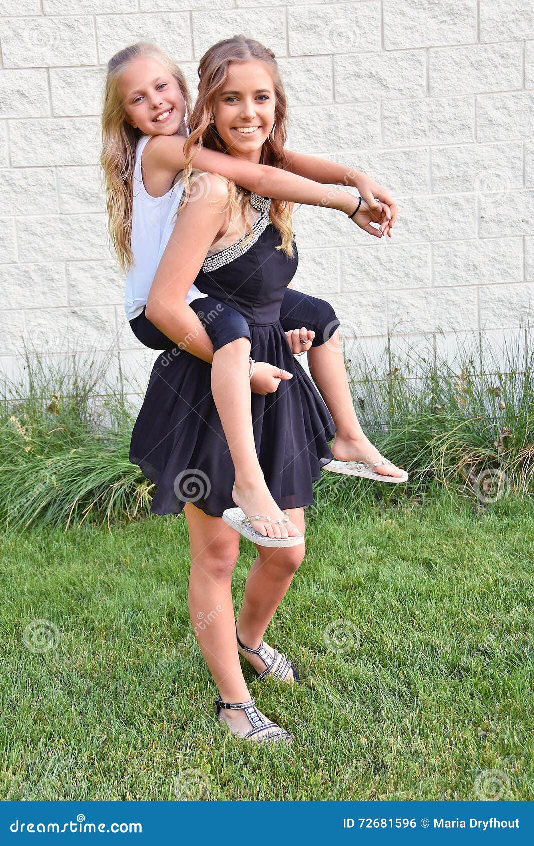 Young girl carrying sister giving piggyback ride Stock Photo