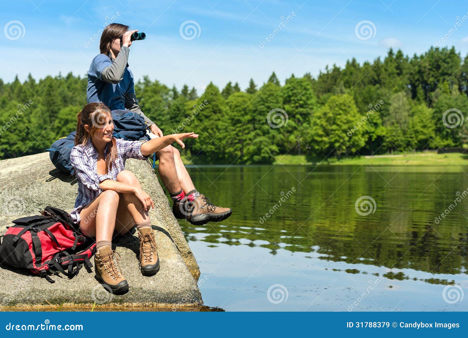 teenage hikers birdwatching at lake