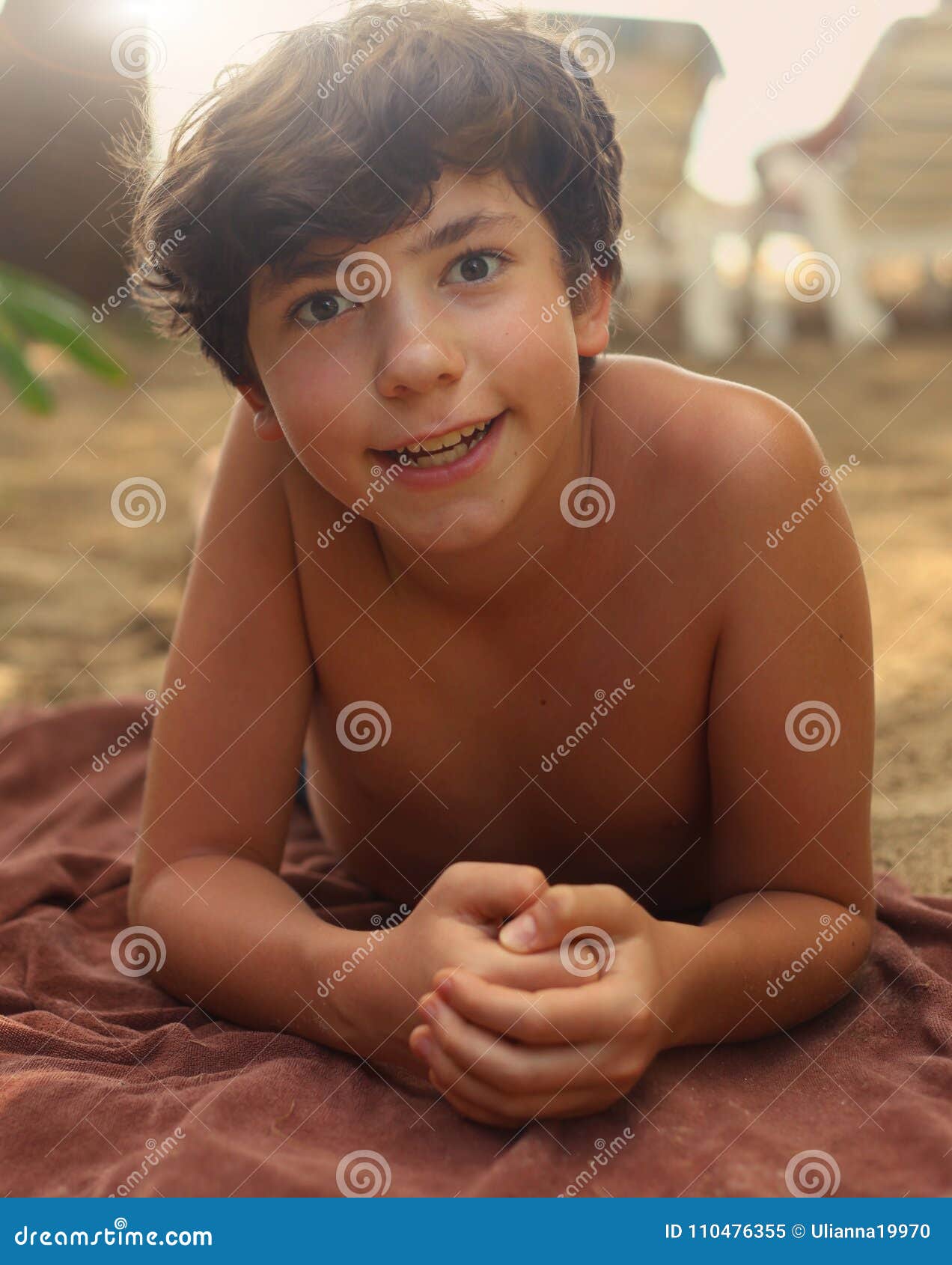 teenager boy with brown tan having sun bath on the beach