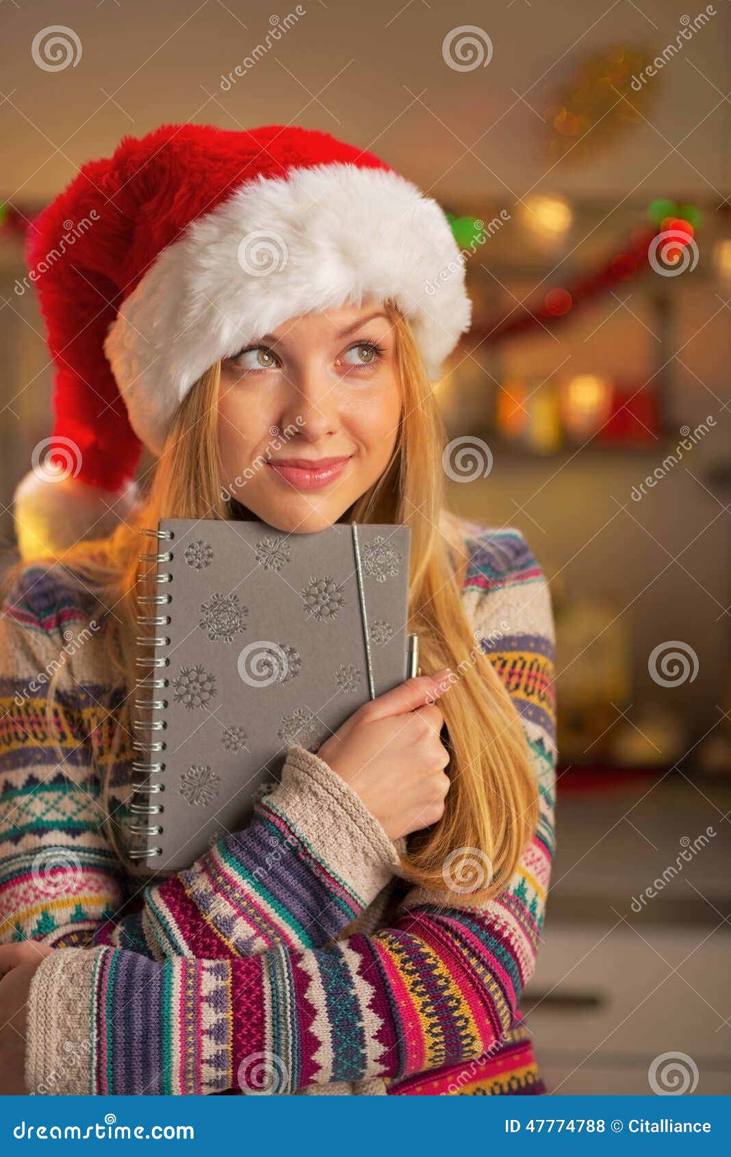 Portrait of teenager girl in santa hat holding notepad