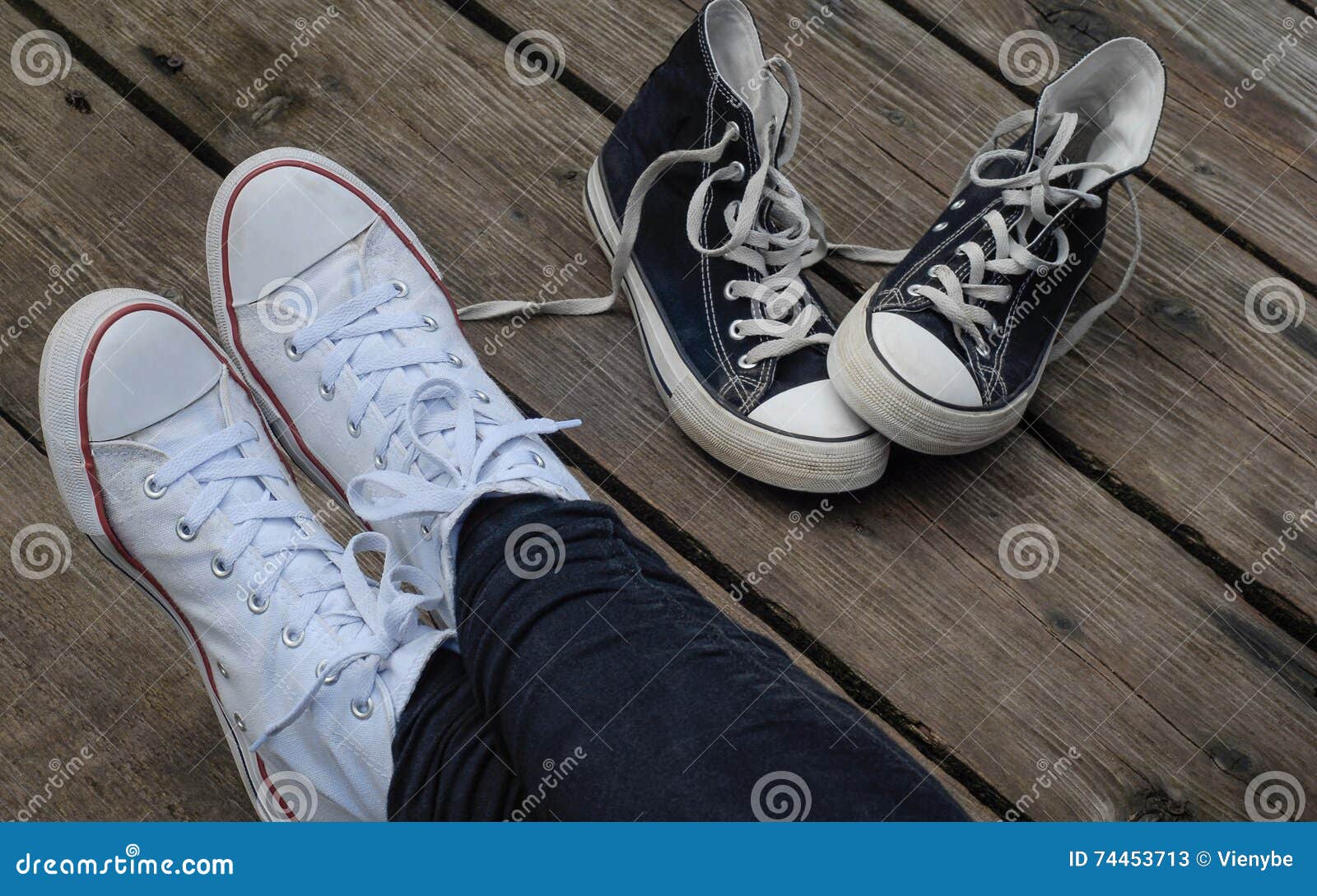 Teenager Wearing White Shoes Sitting Next To Black Snickers, Choice ...