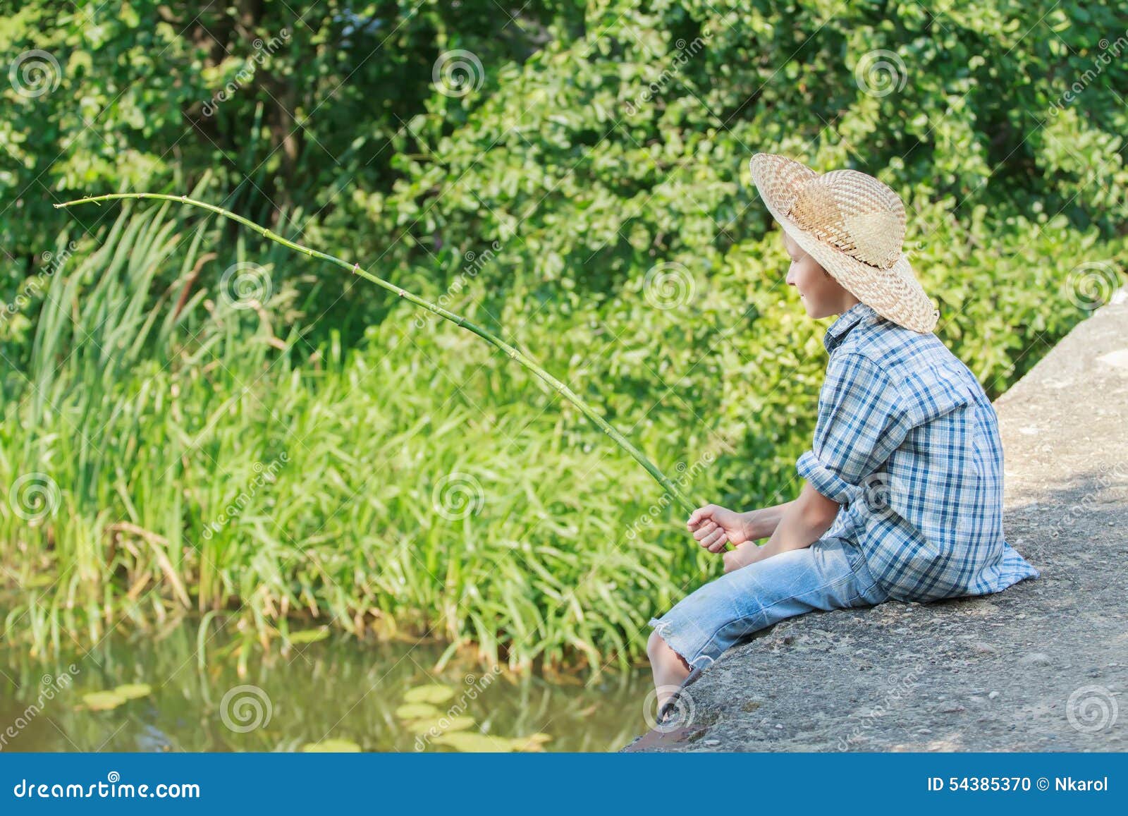 teenager with wooden rustic fishing rod angling on concrete bridge