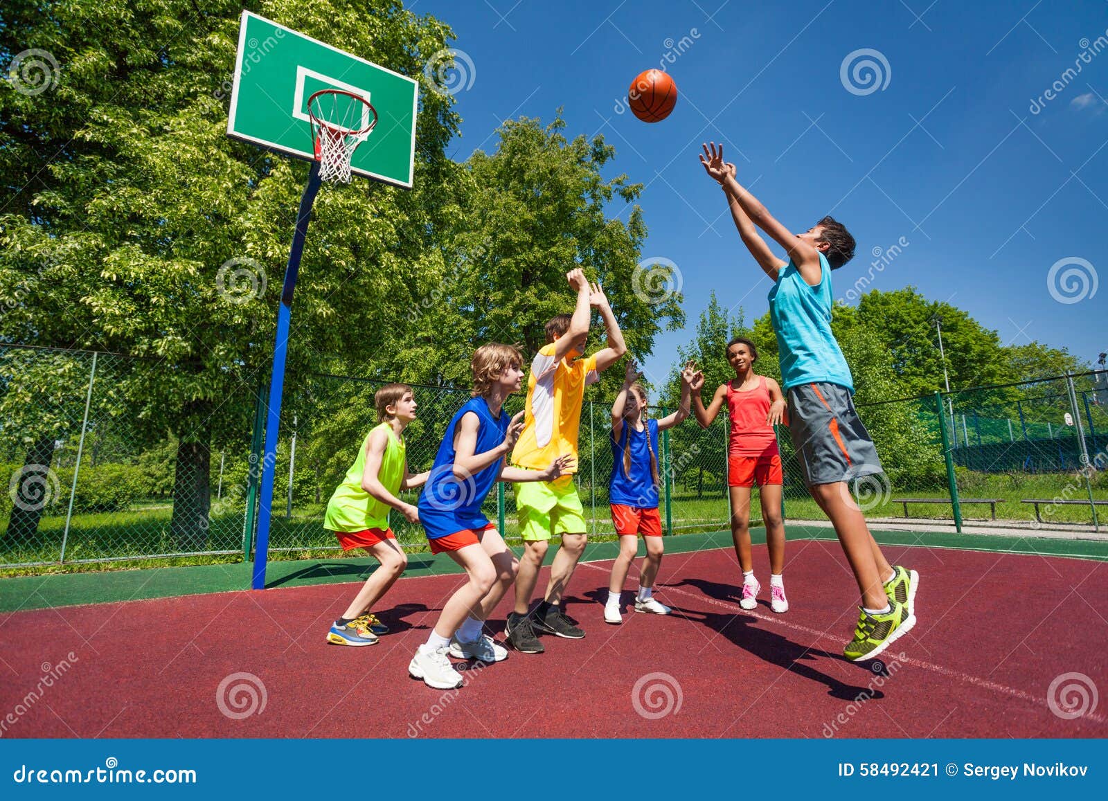 teenagers playing basketball game together