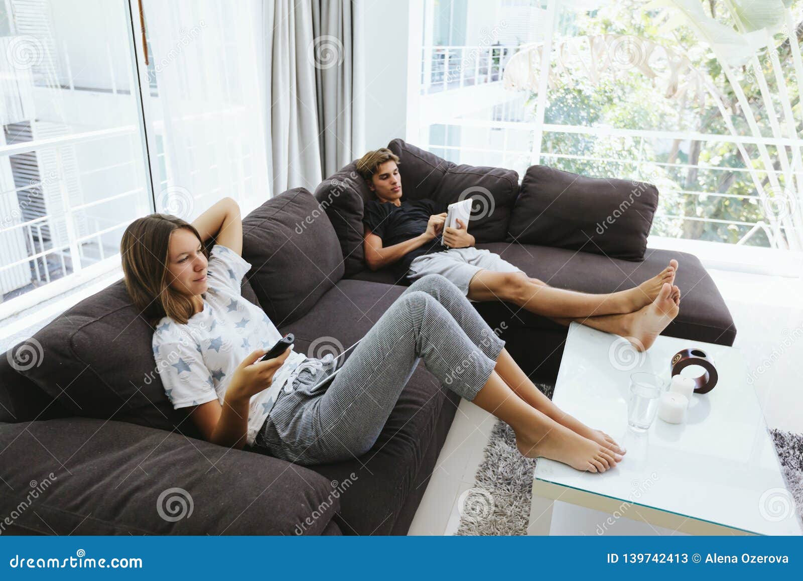 Teenagers Using Tablet Pc And Watching  Tv  On Couch  Stock 