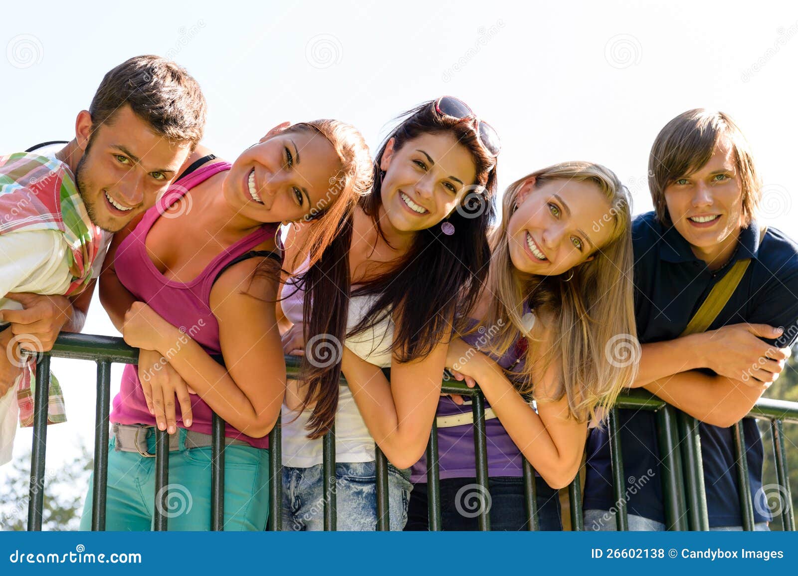 teens having fun in park leaning fence