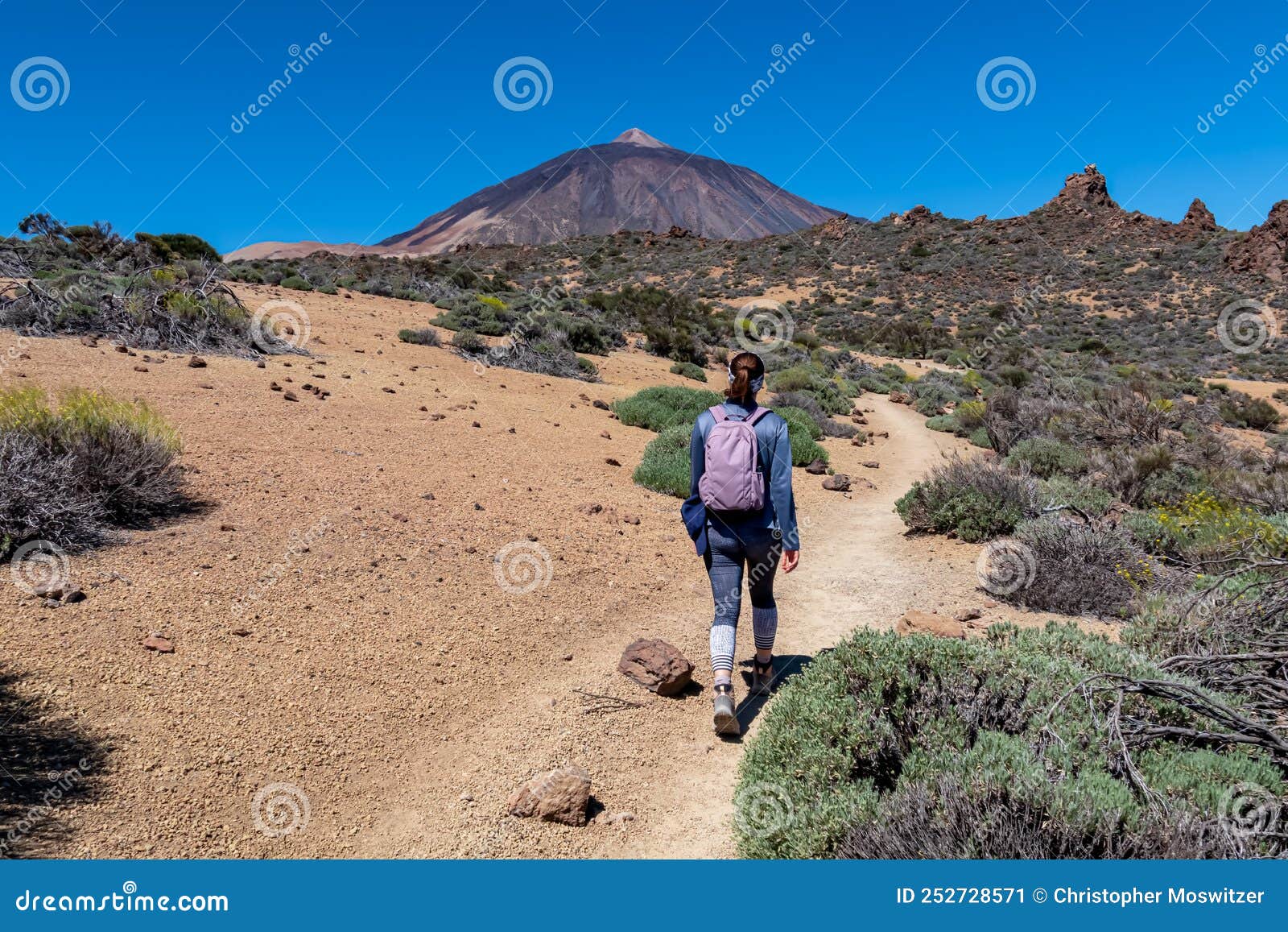 teide - woman on hiking trail la fortaleza from el portillo. panoramic view on volcano pico del teide