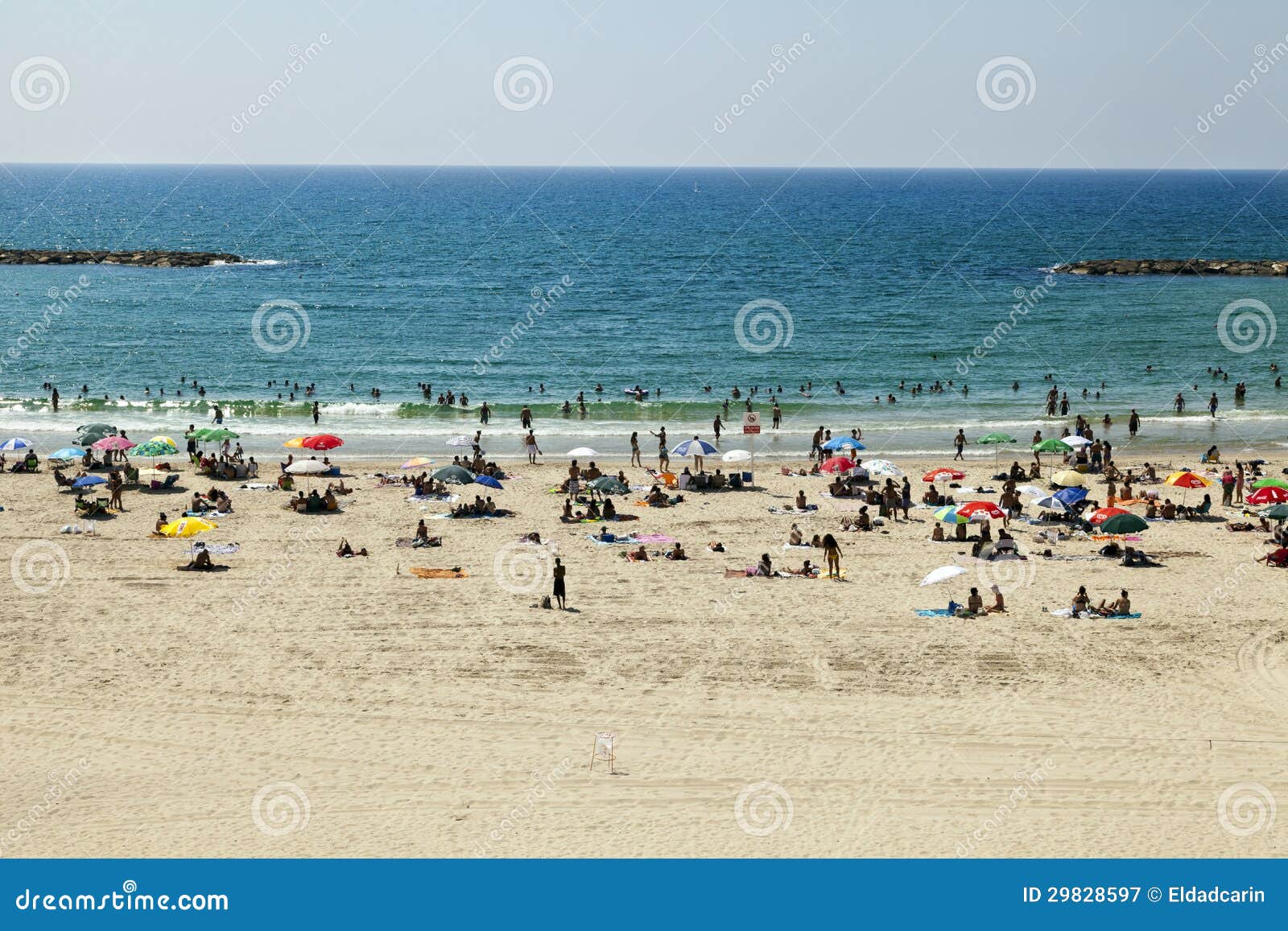 De zomer bij het Strand in Tel Aviv. Tel Aviv, Israël - Augustus achttiende, 2012: Hoge hoekmening van het strand in Tel Aviv, die met mensen op een hete de zomerdag wordt ingepakt.