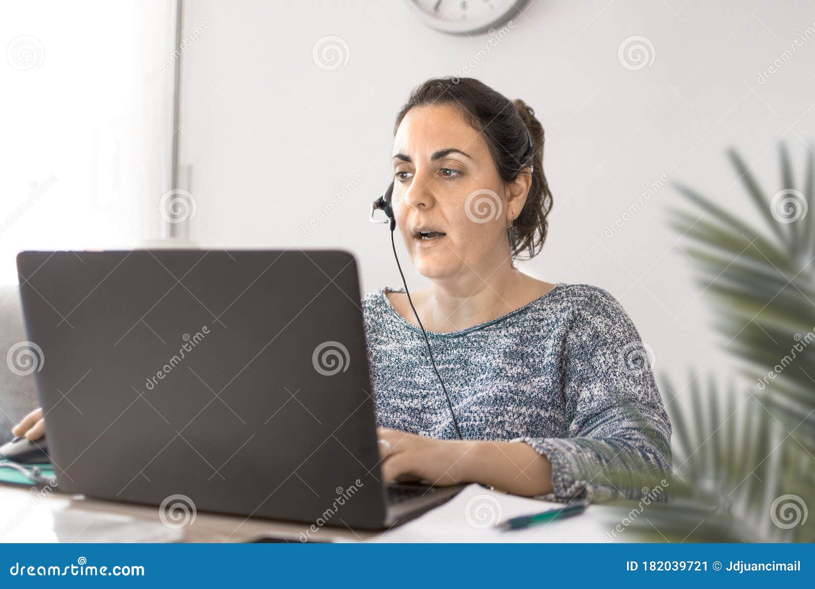 teleworking woman with a headphones and a laptop computer at home in the livingroom. telework concept and empty copy space
