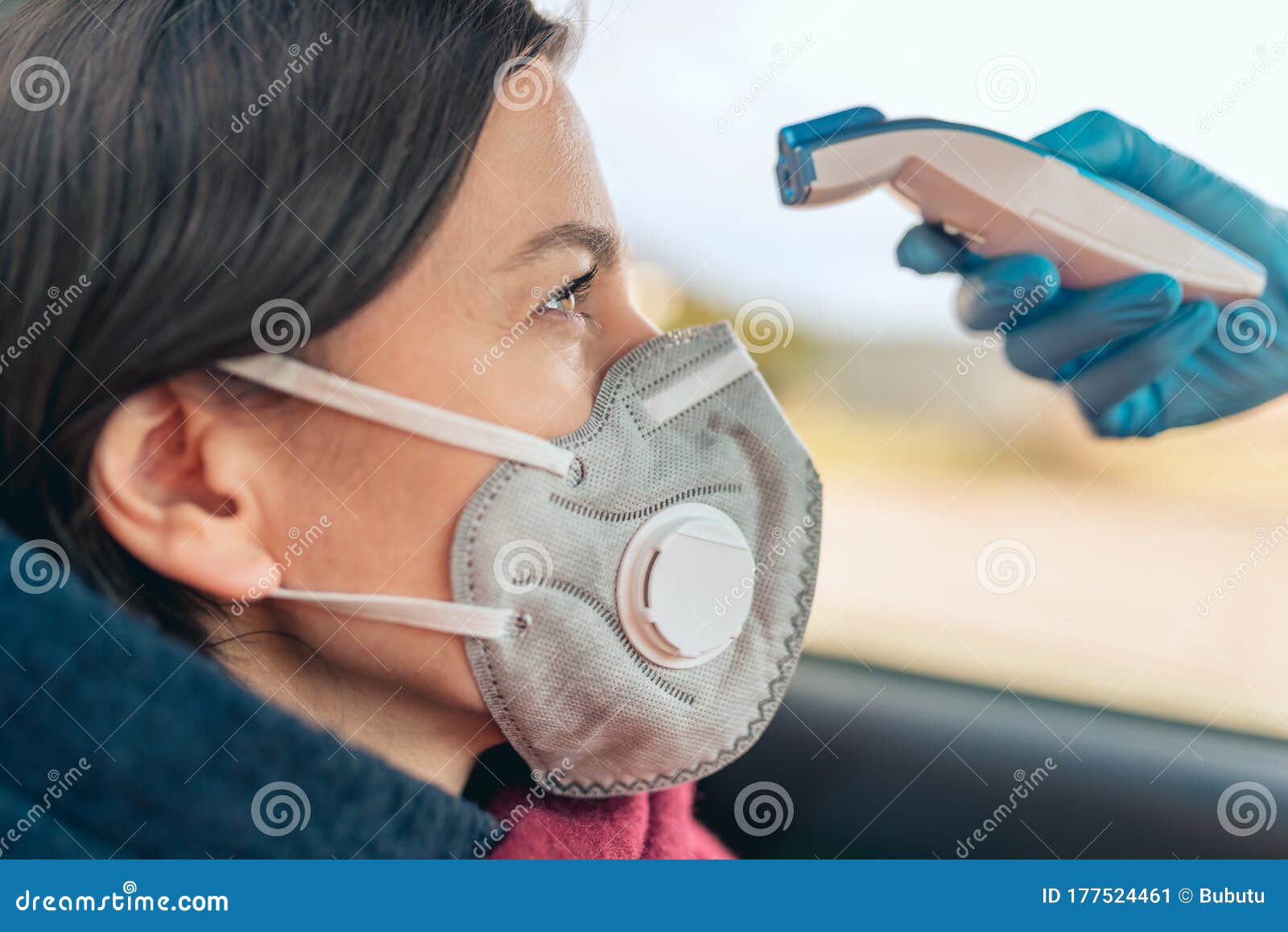 temperature check point - the woman behind the wheel of the car in an anti-virus mask is subjected to temperature measurement