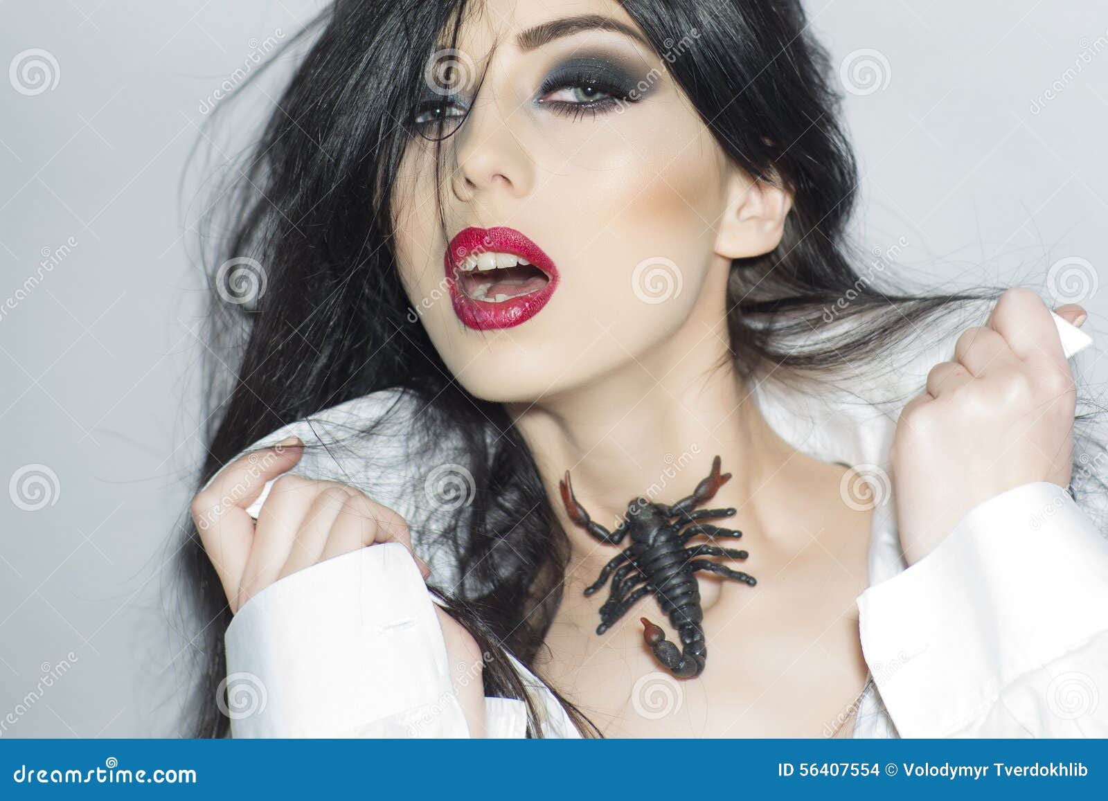 udobnost, izazov - Page 16 Tempting-girl-scorpion-portrait-young-brunette-bright-makeup-red-lips-white-blouse-holding-standing-light-grey-56407554