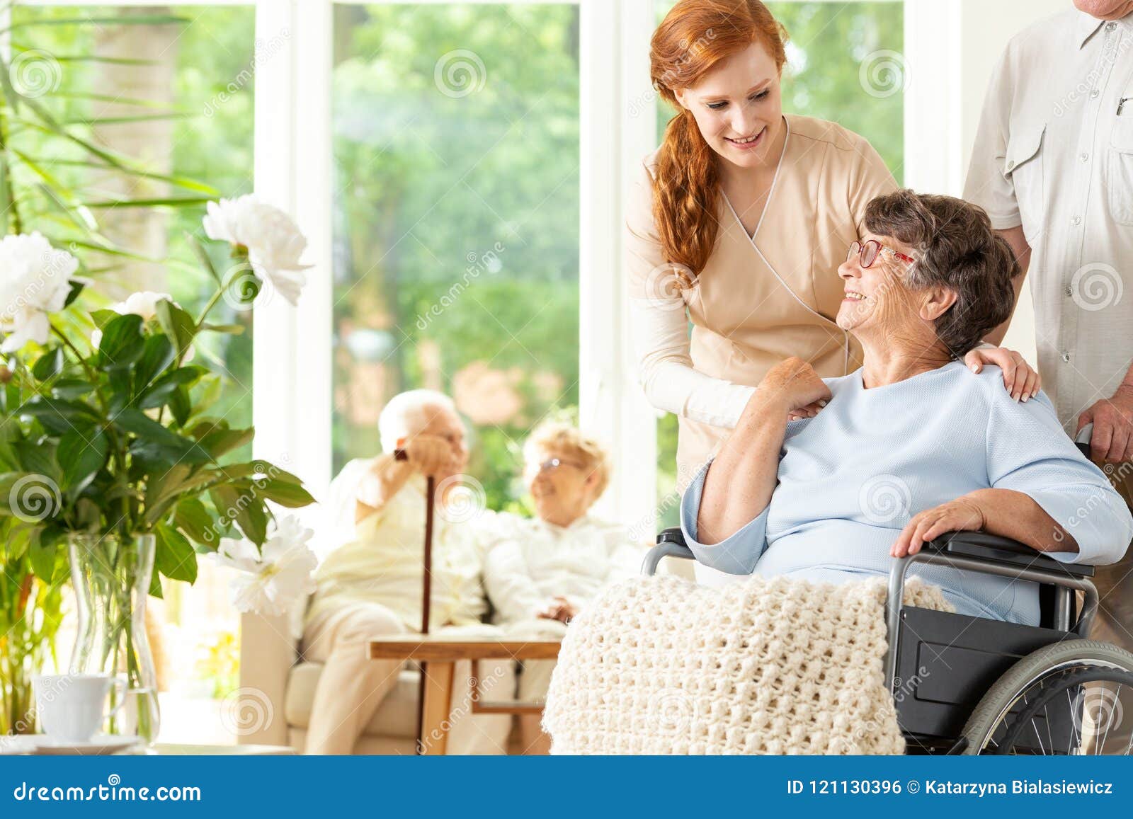 tender caregiver saying goodbye to an elderly pensioner in a wheelchair in a day care facility. a companion pushing