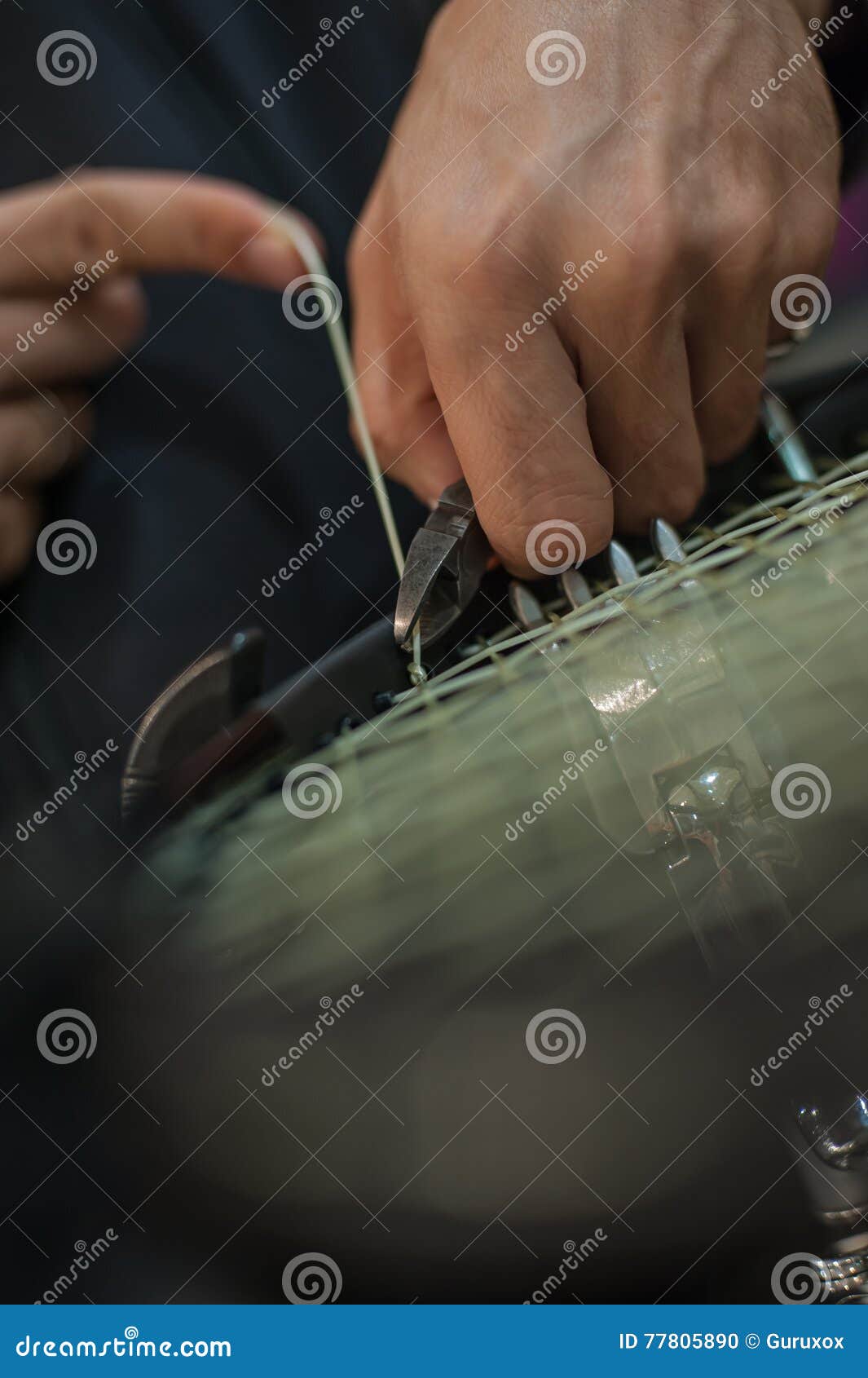 Tennis Stringer Tying Knots and Cutting String with Pliers Stock Photo
