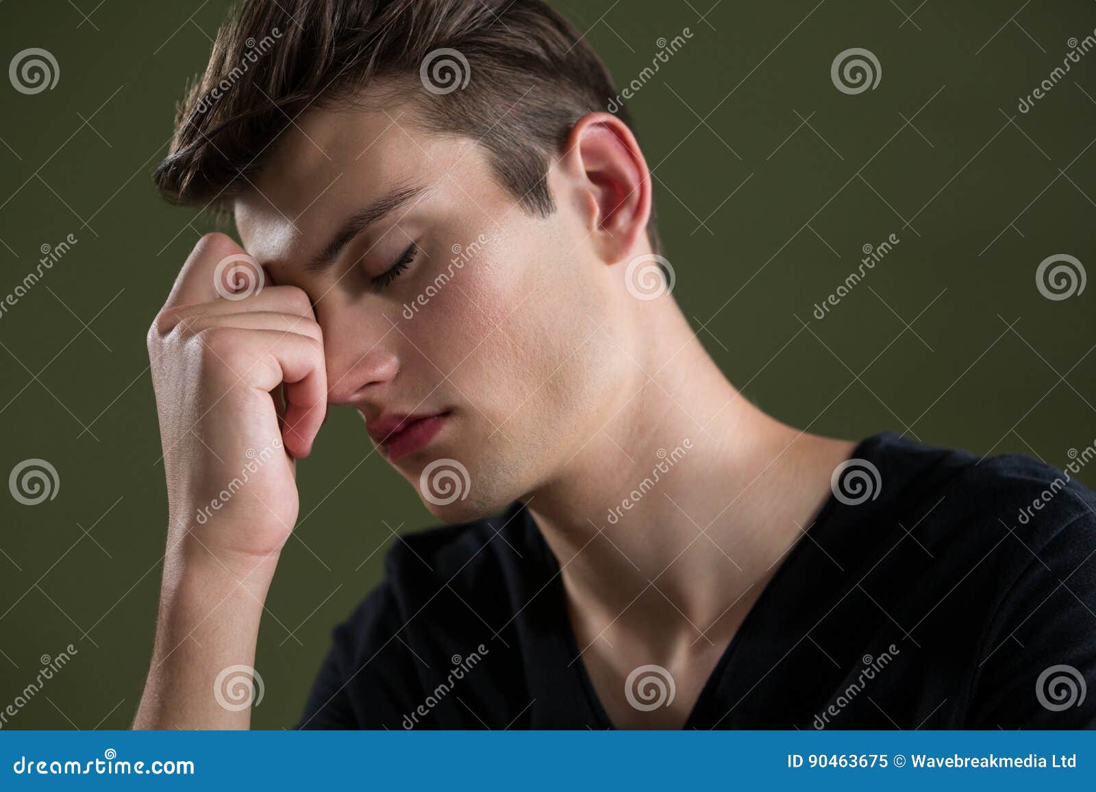 tense androgynous man with hand on forehead
