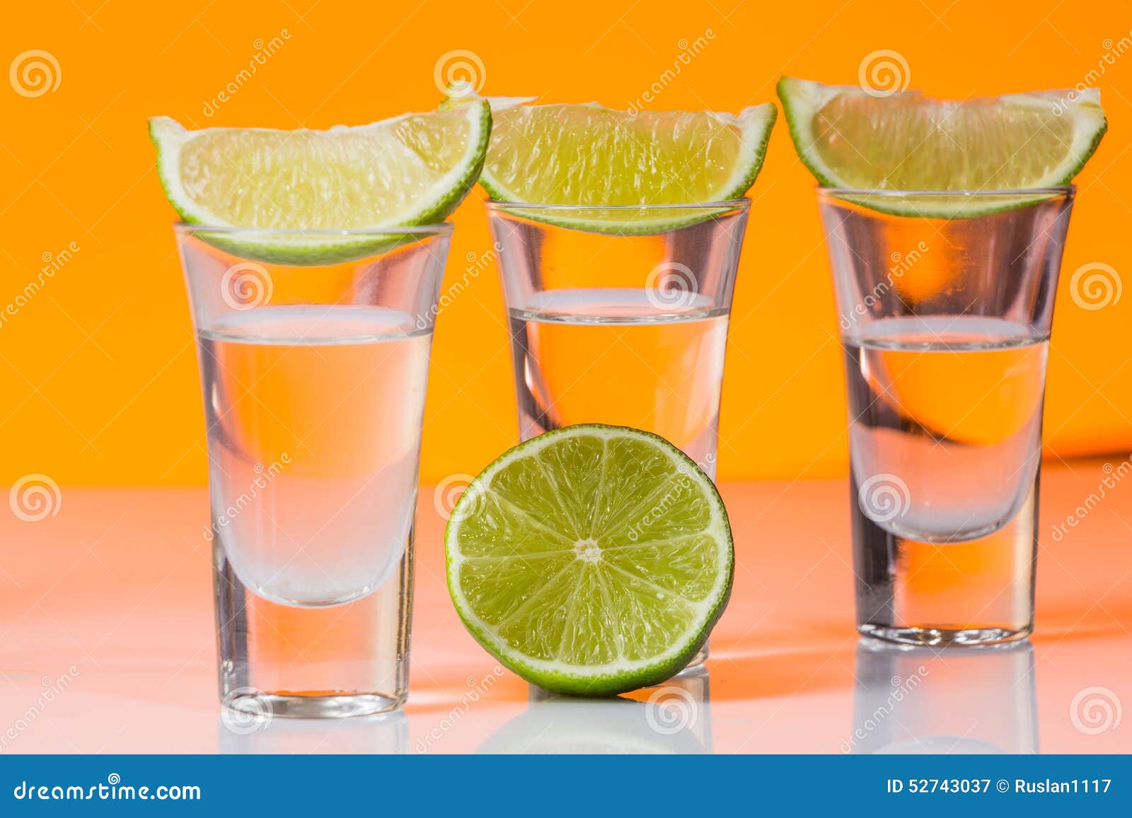 Tequila Shot with a Slice of Lime on the Glass Orange Background Stock ...