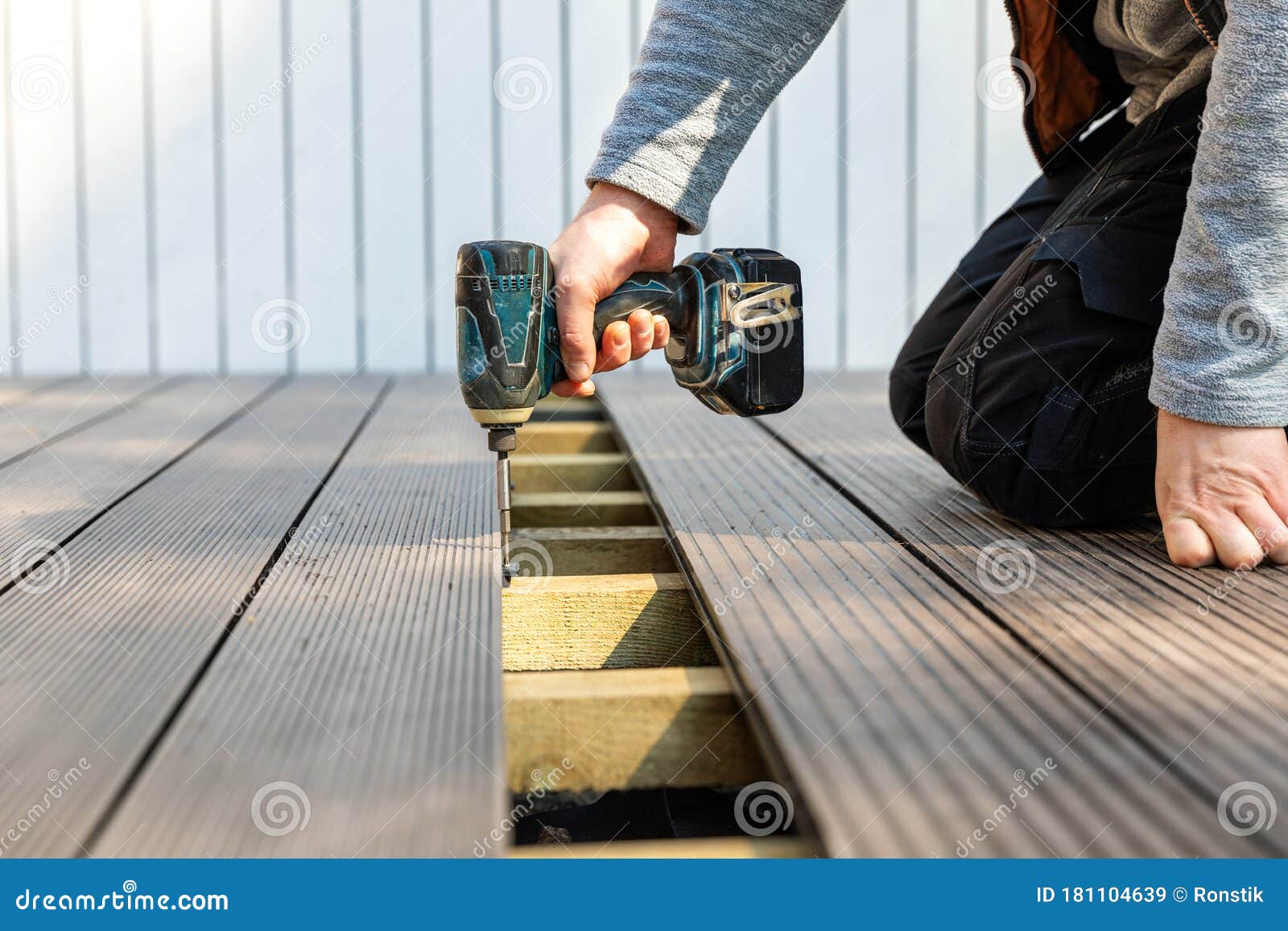 terrace deck construction - man installing wpc composite decking boards