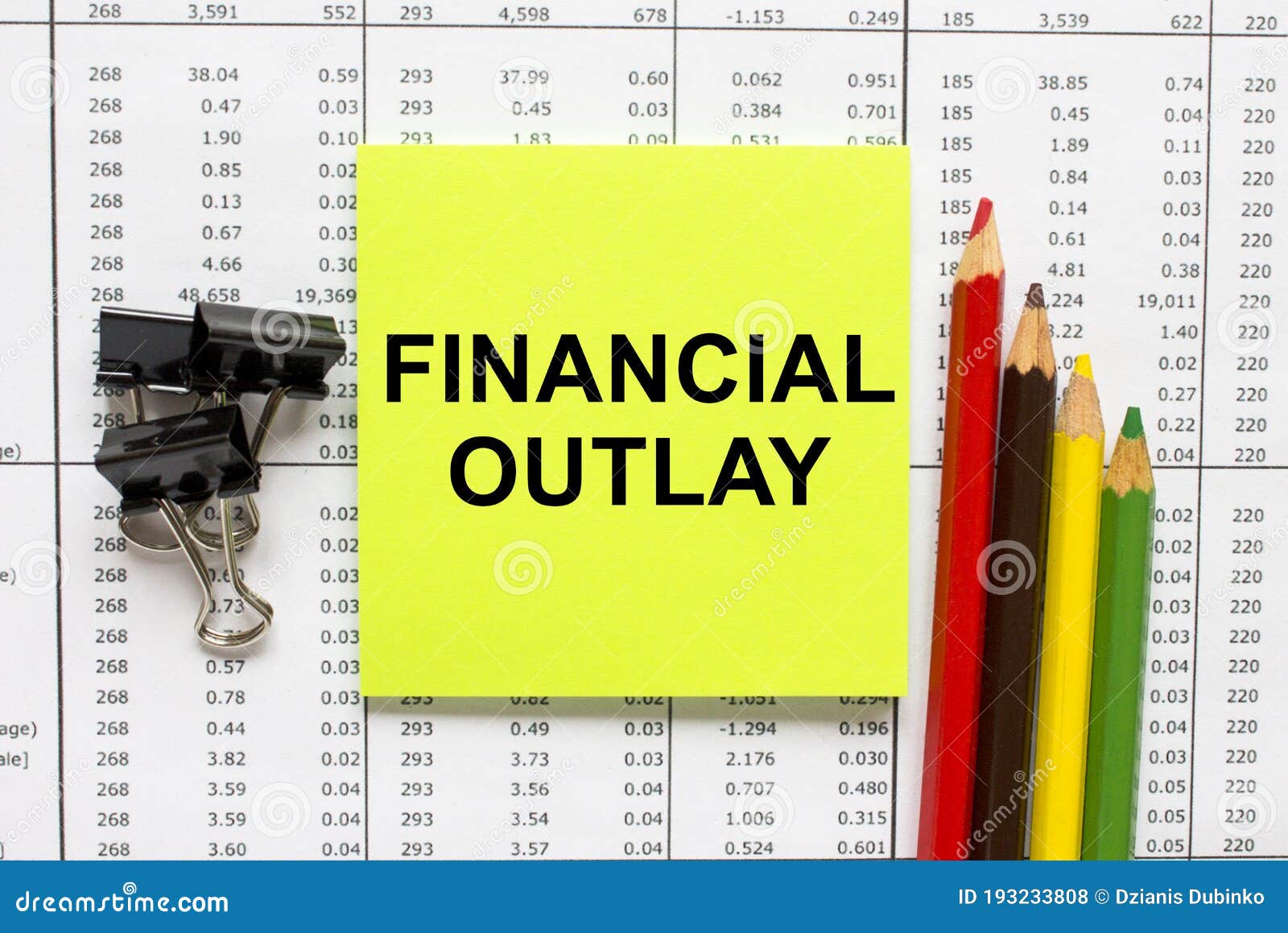 text financial outlay on financial tables with pencils, glasses and paper clips