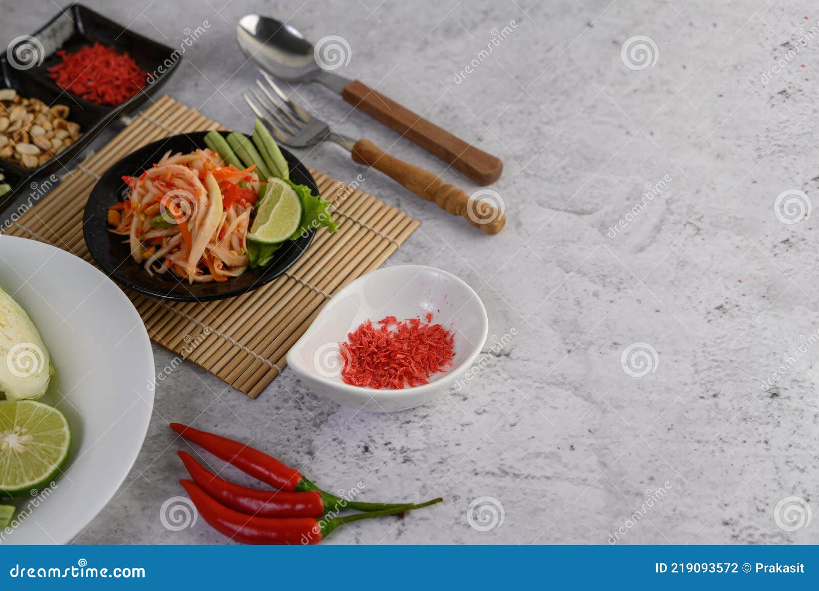 Thai Papaya Salad in a White Plate with Spoon, Fork, and Dried Shrimp