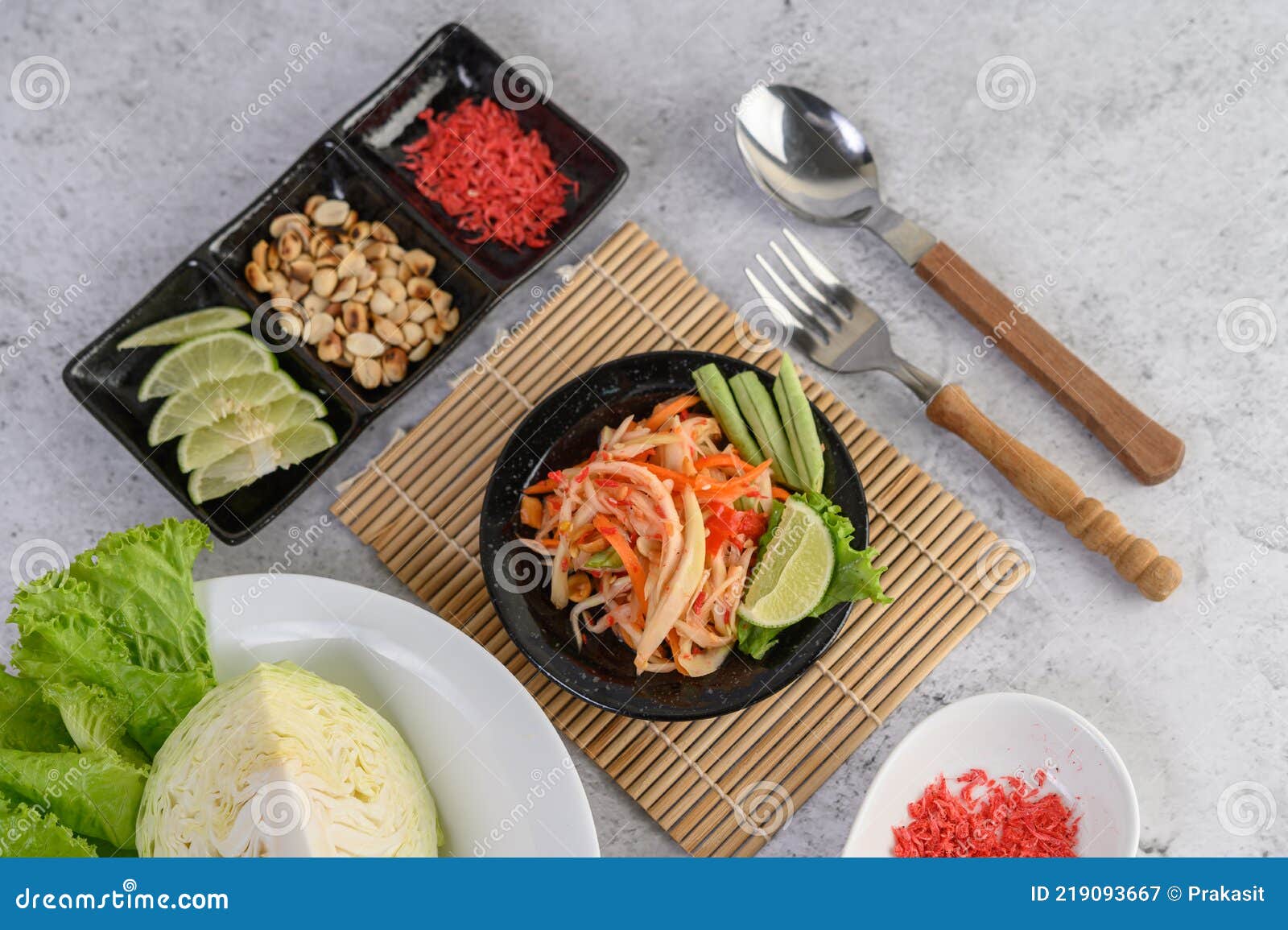 Thai Papaya Salad in a White Plate with Spoon, Fork, and Dried Shrimp