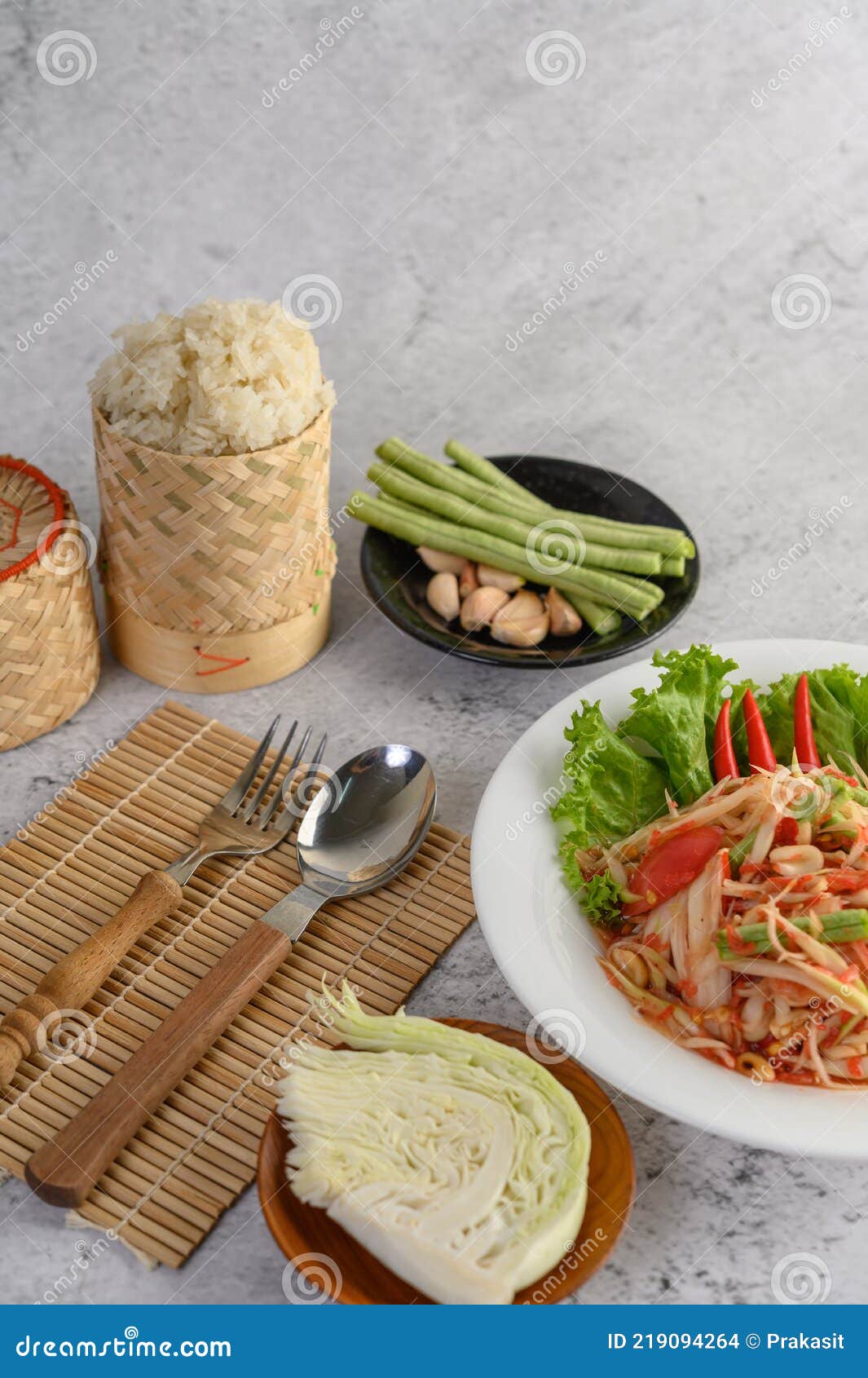 Thai Papaya Salad in a White Plate with Sticky Rice, Spoon, and Fork