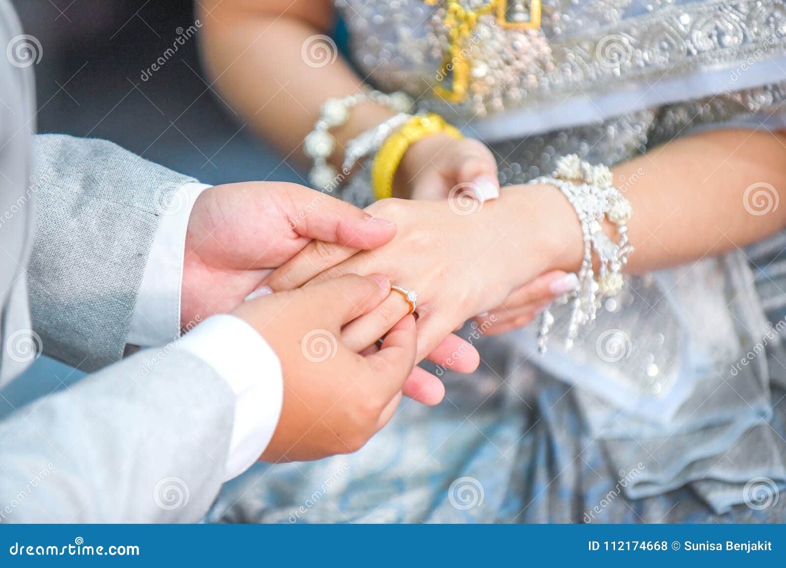 Thai Groom`s Hand Putting a Wedding Ring on the Bride`s Finger. Stock