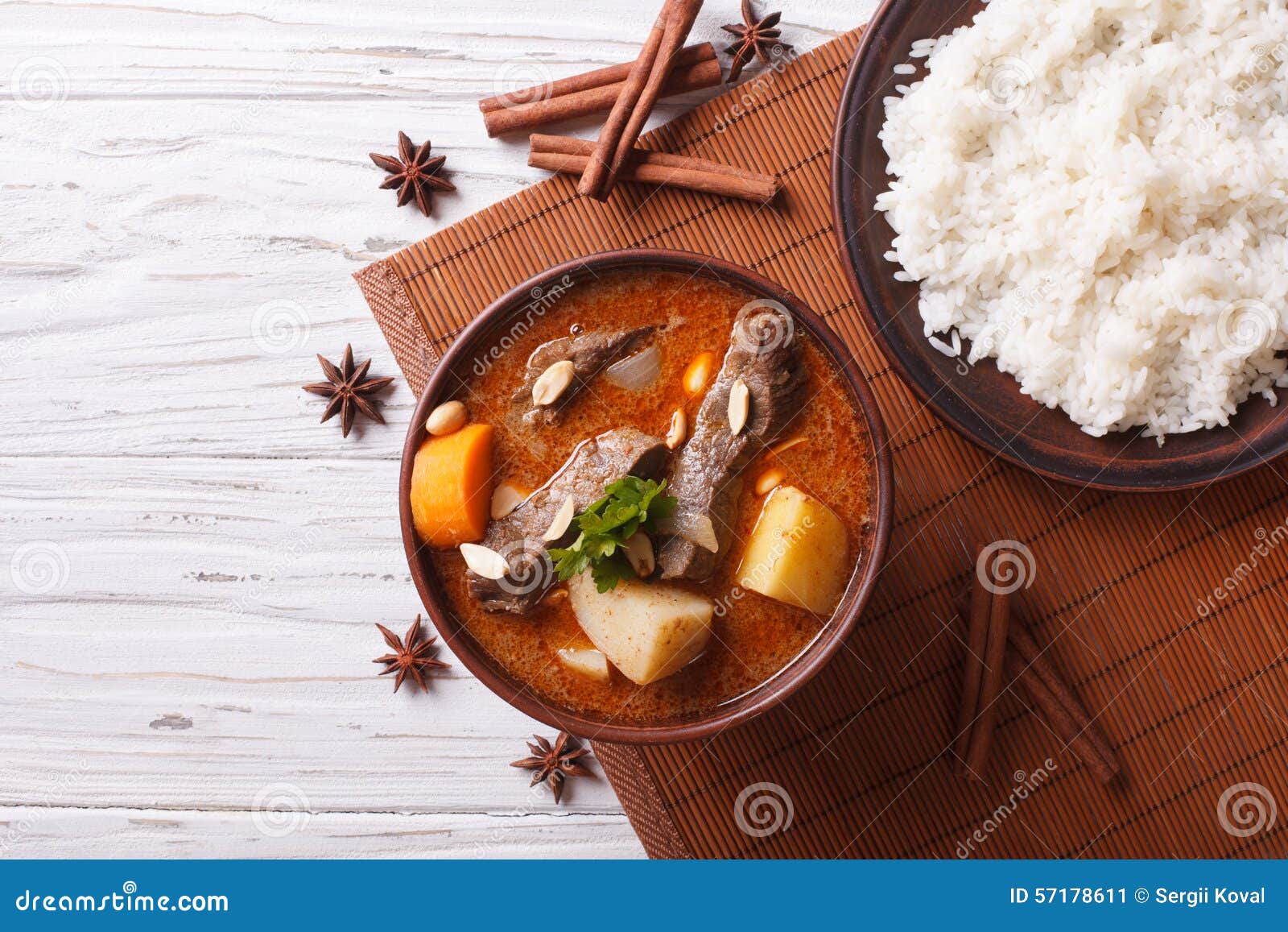 Thailändische Rindfleisch massaman Curry- und Reisbeilage horizontale Draufsicht. Heißer traditioneller thailändischer Rindfleisch massaman Curry mit Erdnüssen und Reisbeilage horizontale Ansicht von oben