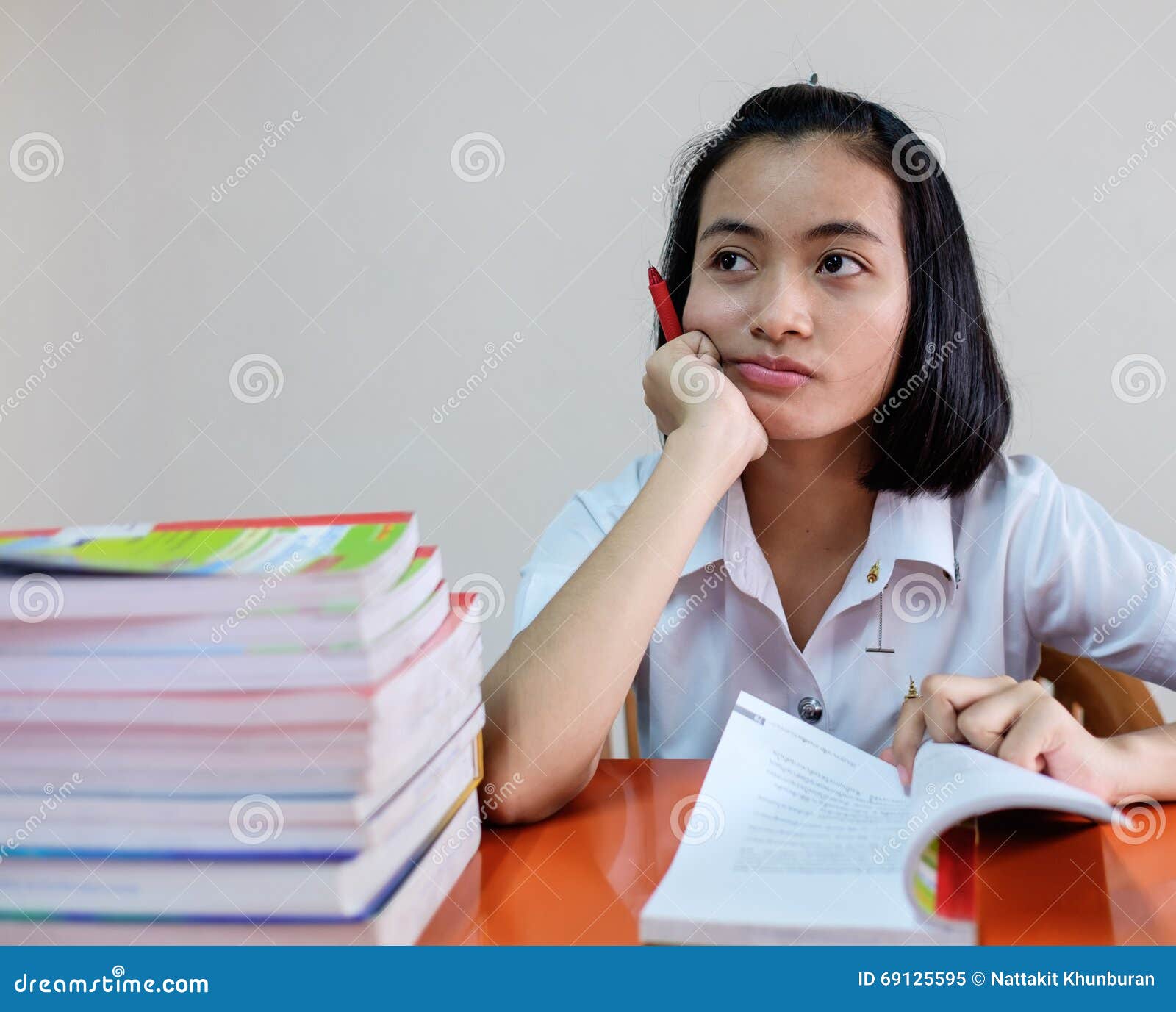 Selectieve nadruk op Thaise jonge volwassen studente in eenvormige lezing een boek dichtbij lijst met spanning