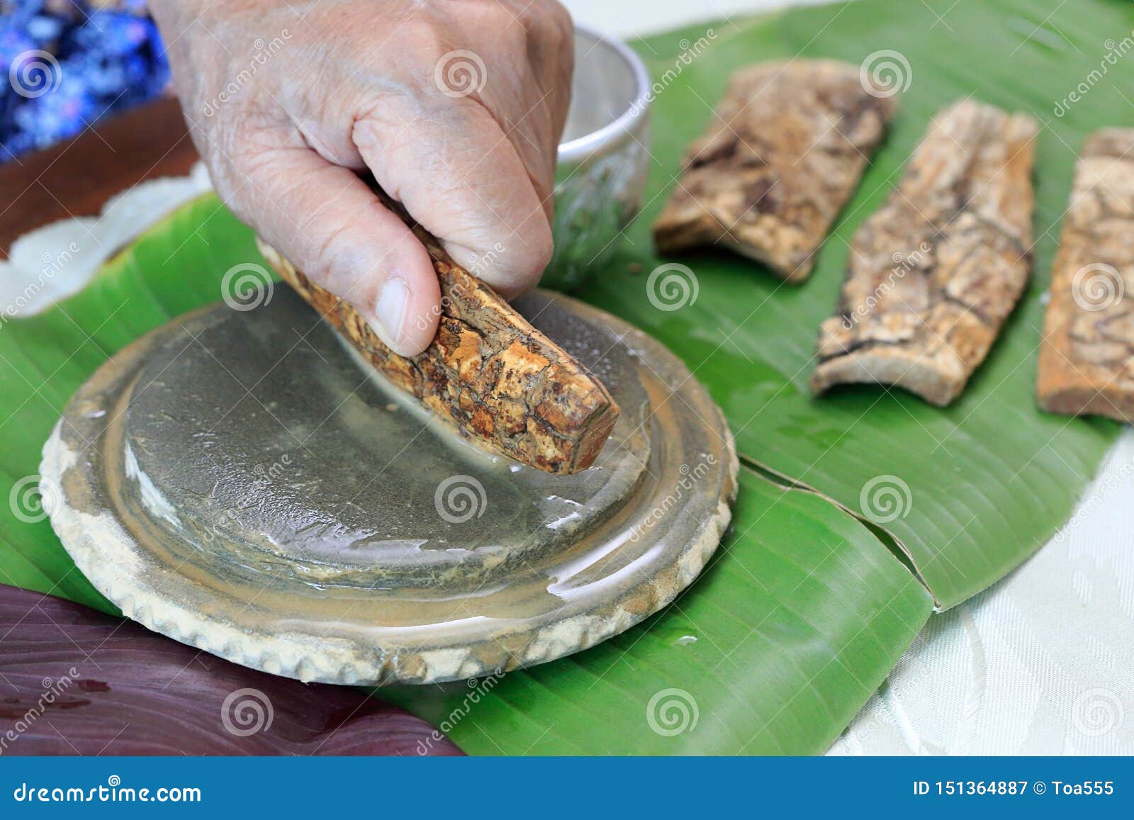 thanaka herb bark scrubbing on kyauk pyin stone slab