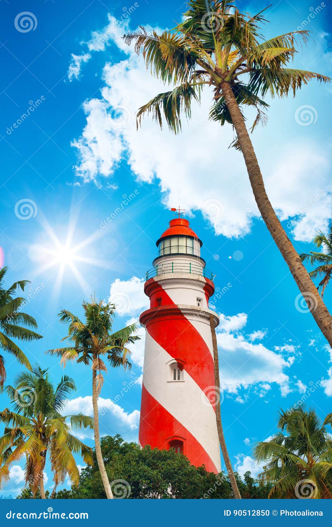 thangassery lighthouse on the cliff surrounded by palm trees and big sea waves on the kollam beach. kerala, india