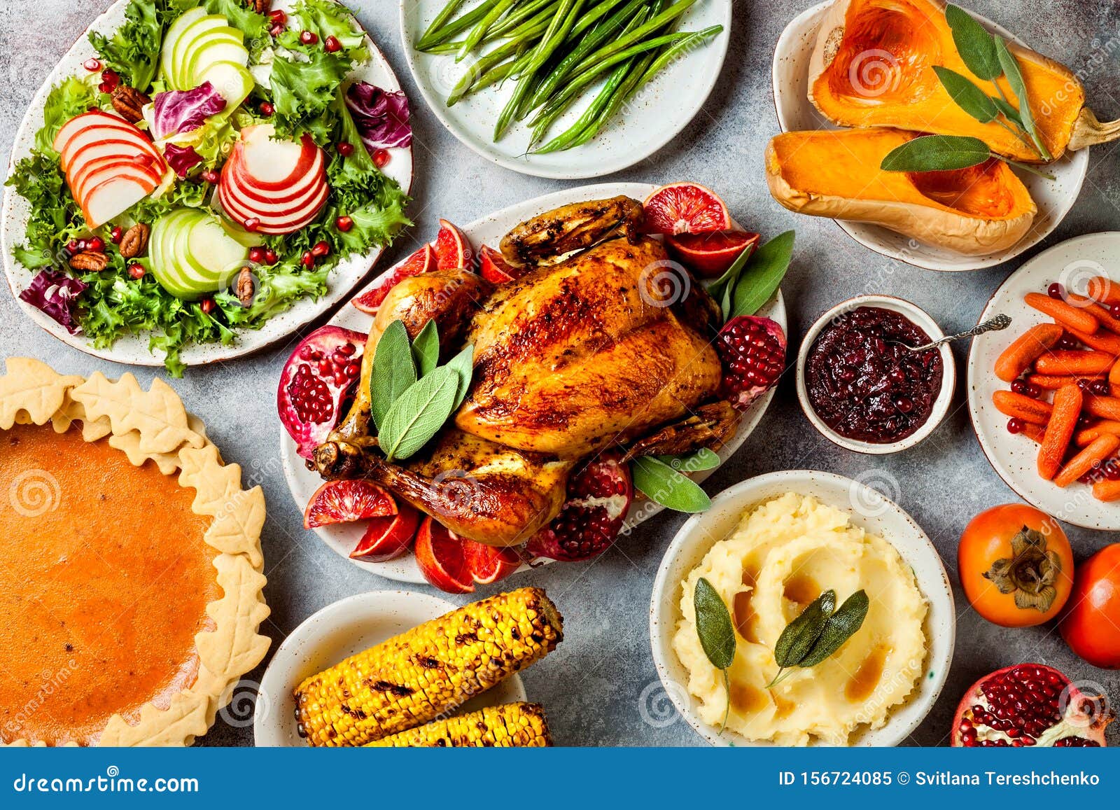 thanksgiving dinner table with roasted whole chicken or turkey, green beans, mashed potatoes, cranberry sauce, grilled vegetables