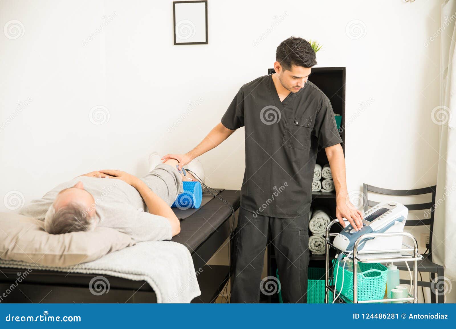 Therapist Positioning Electrodes on Patient`s Knee in Hospital Stock