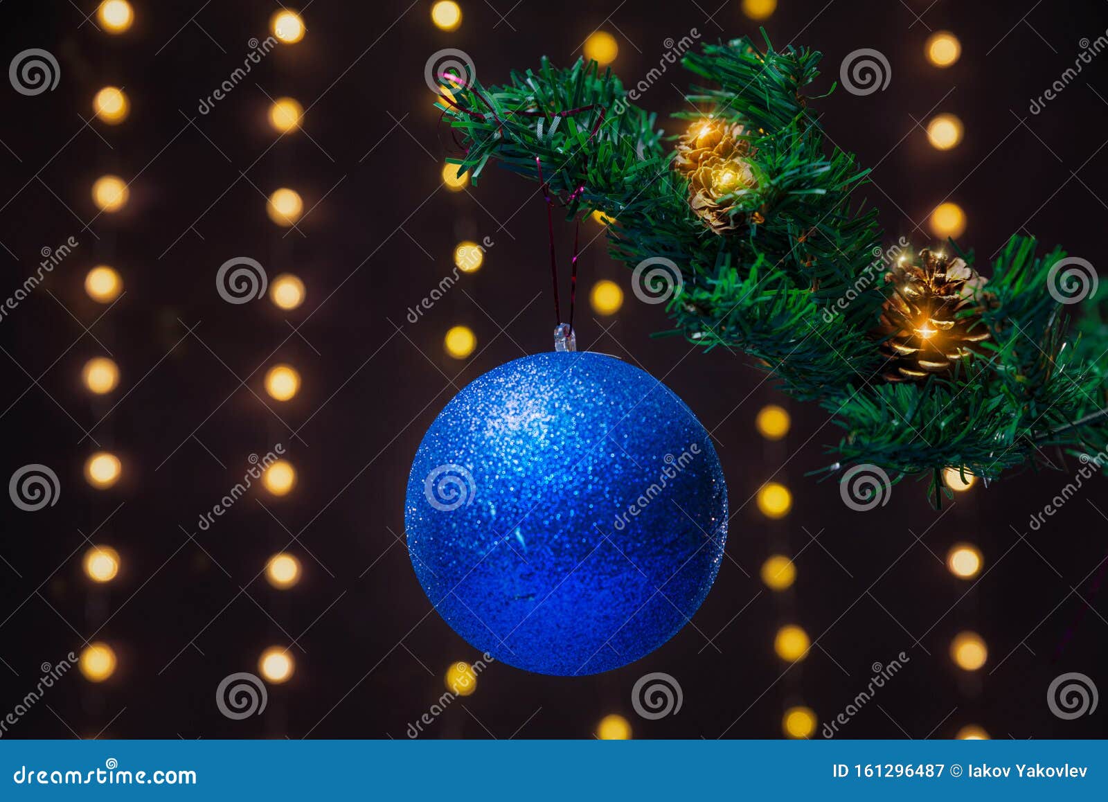 There is Blue Ball on the Green Xmas Tree Branch. There are Glowing ...