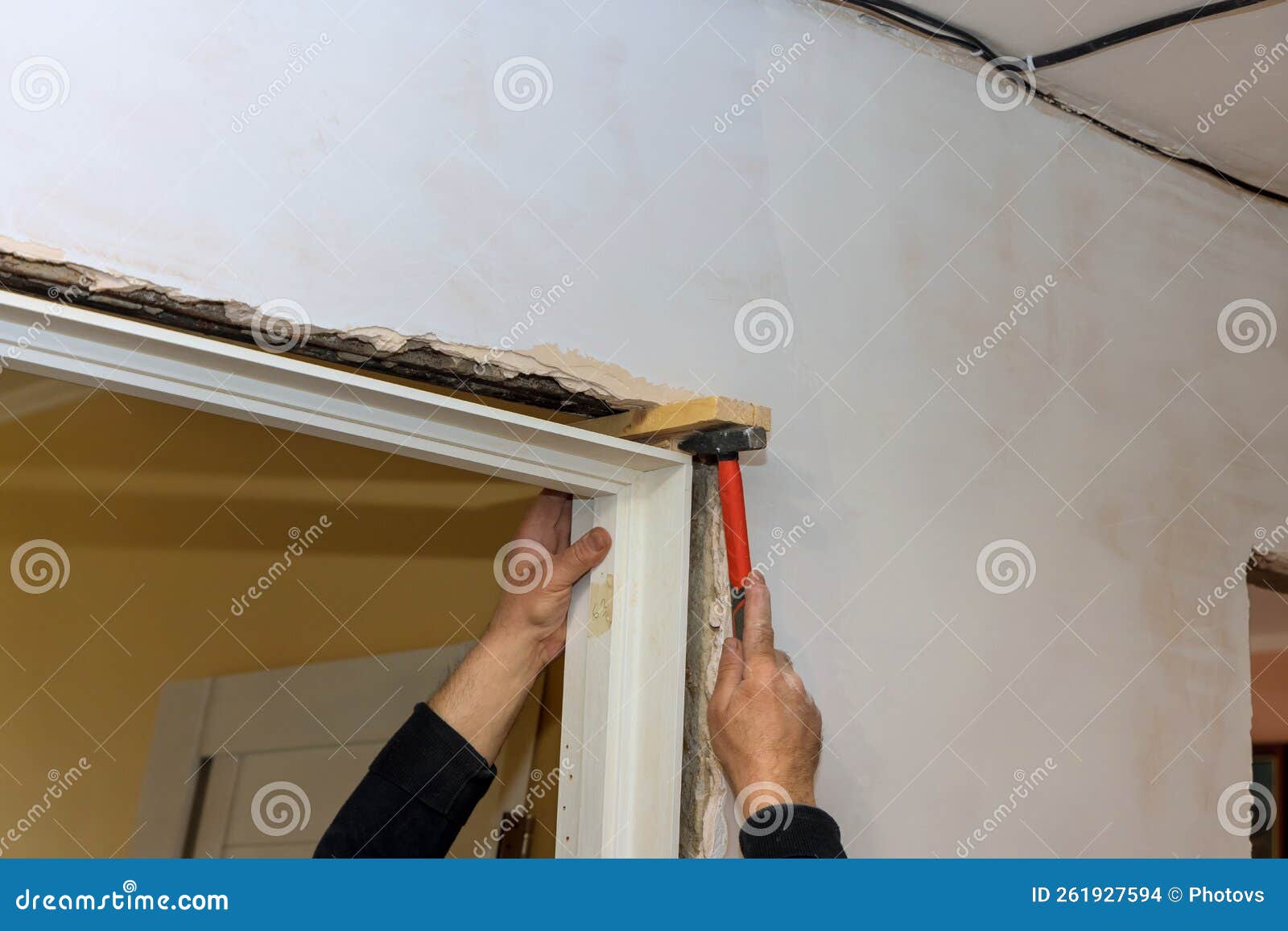 There of a Trim Worker Using a Hammer during the Installation of