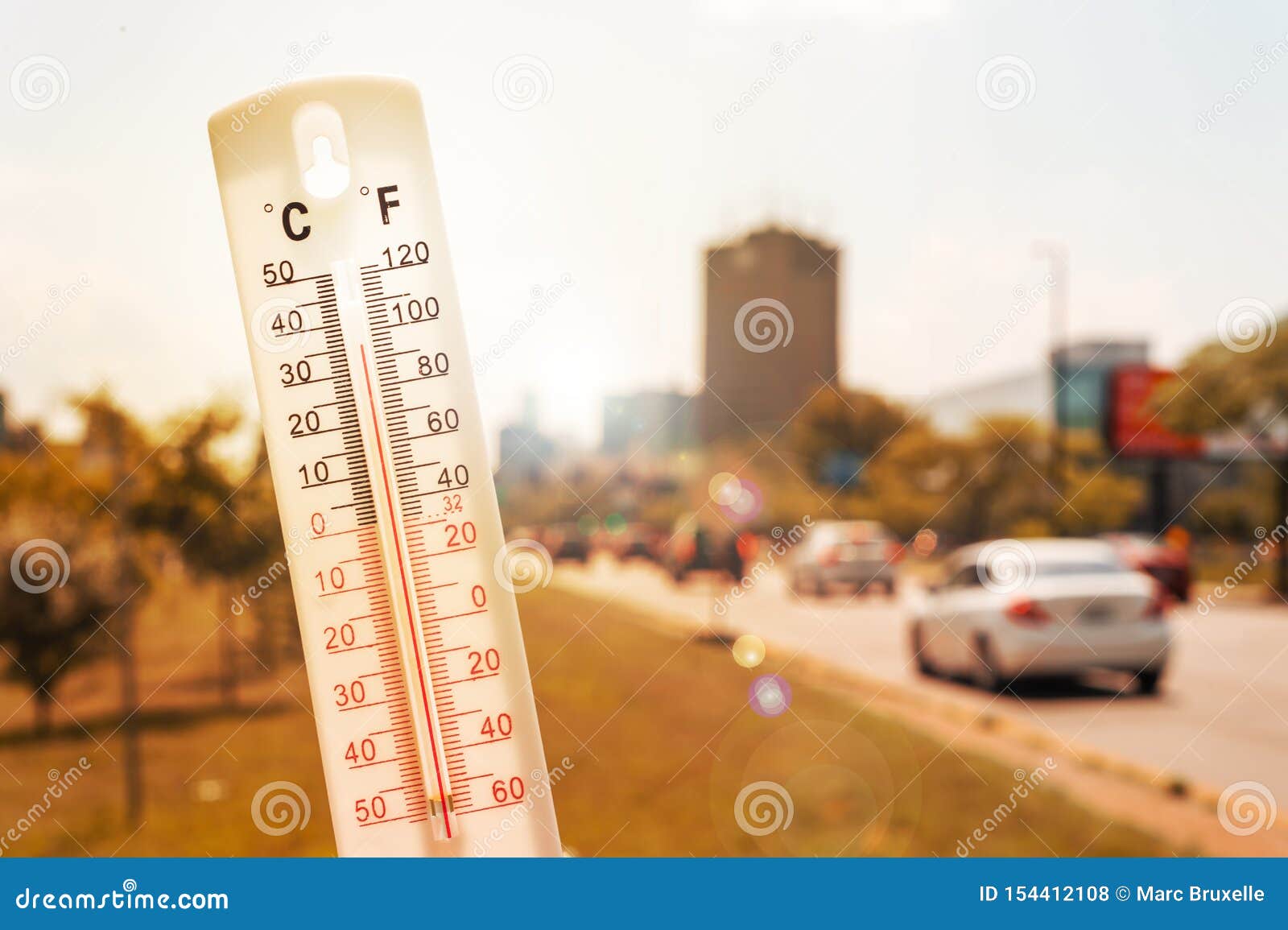 thermometer in front of cars and traffic during heatwave