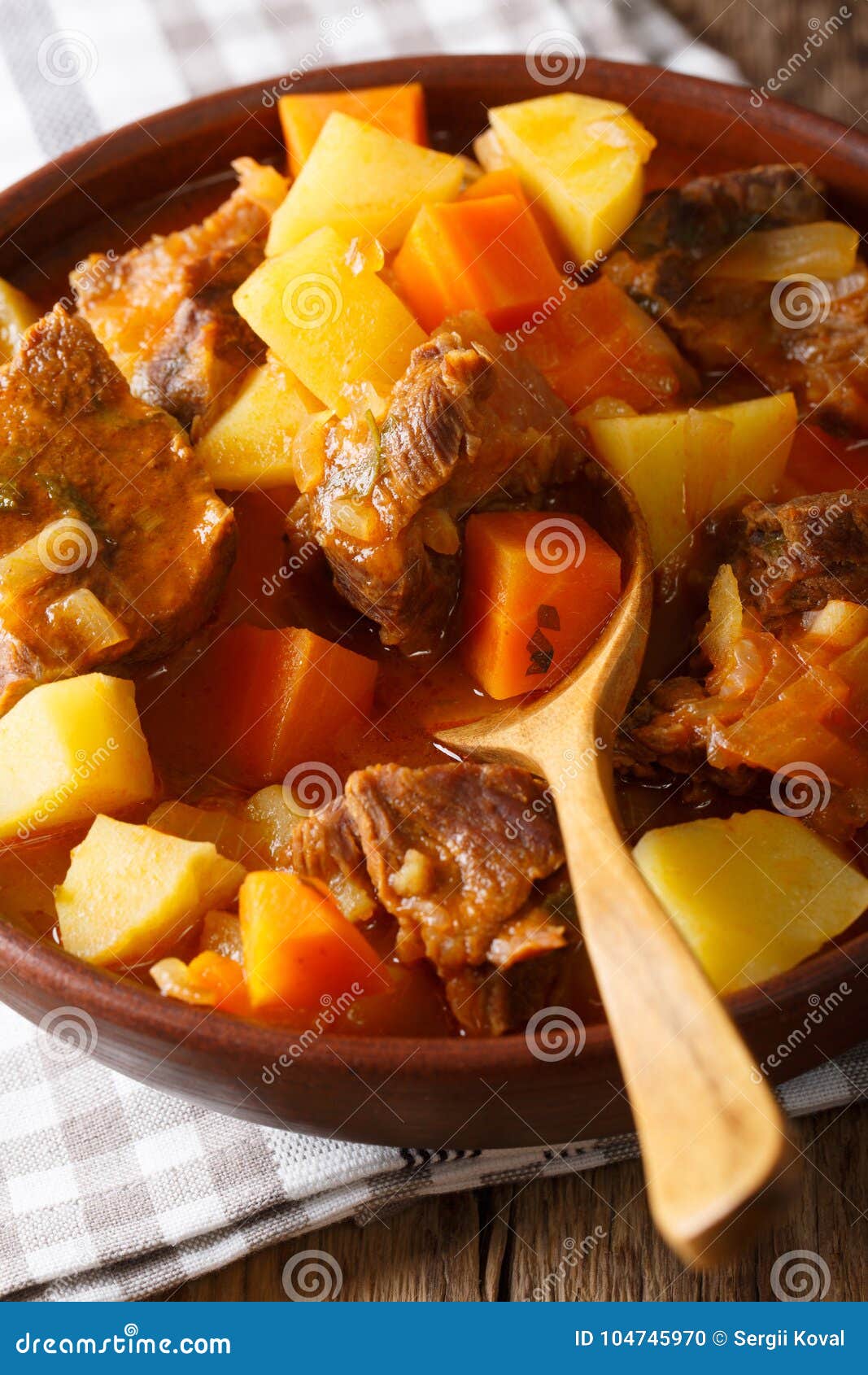 thick stewed estofado with beef and vegetables close-up. vertical