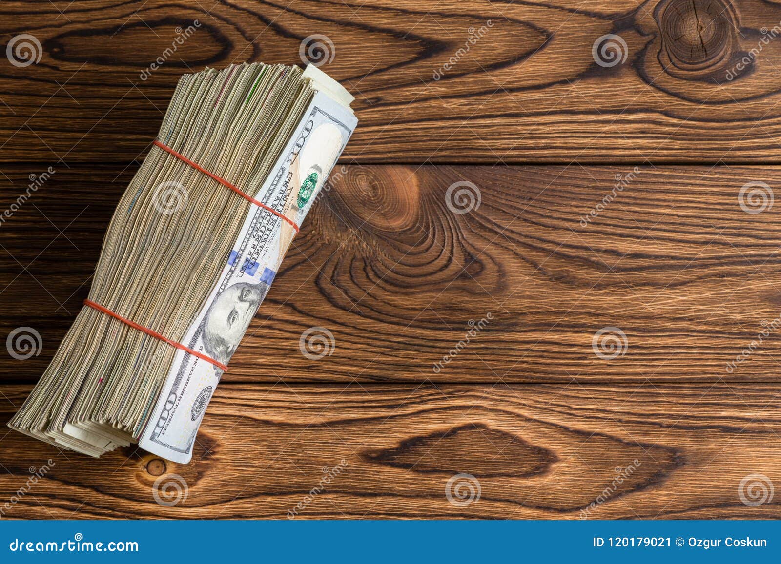thick wad of used 100 dollar bills on rustic wood