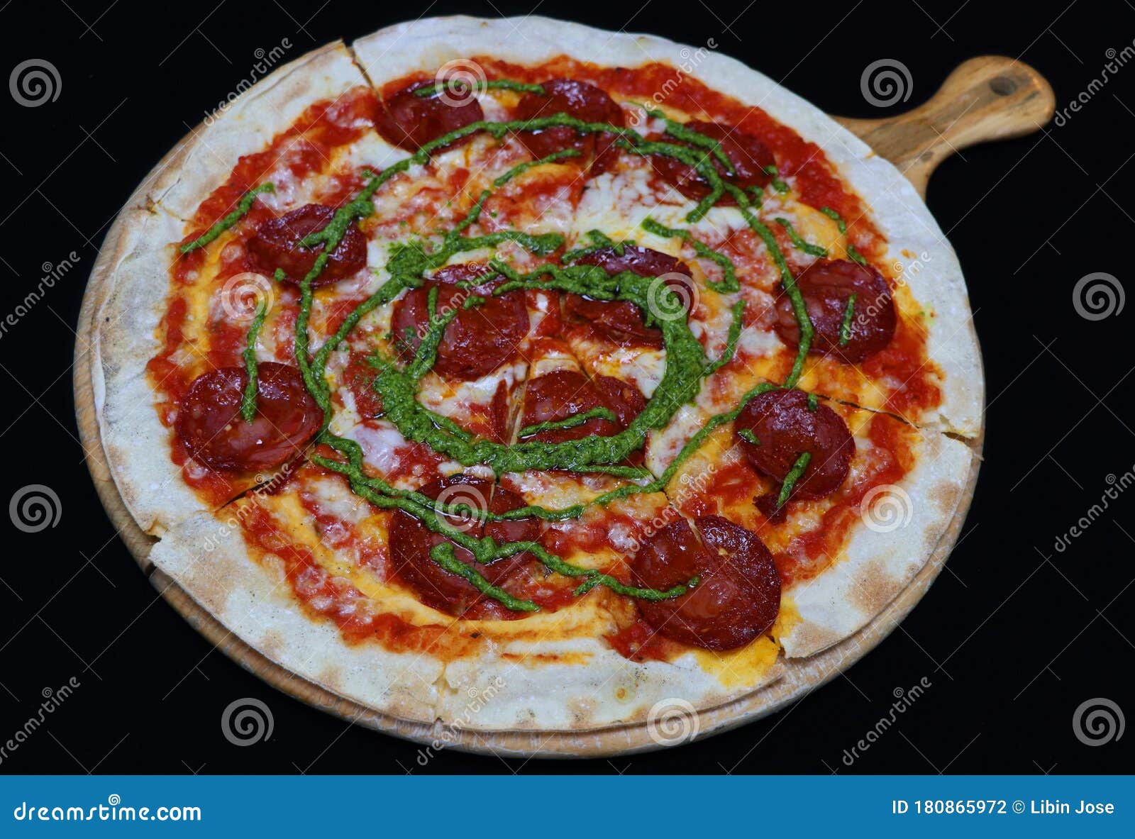 Thin Crust Beef Pepperoni Pizza with Basil Pesto Sauce Stock Photo