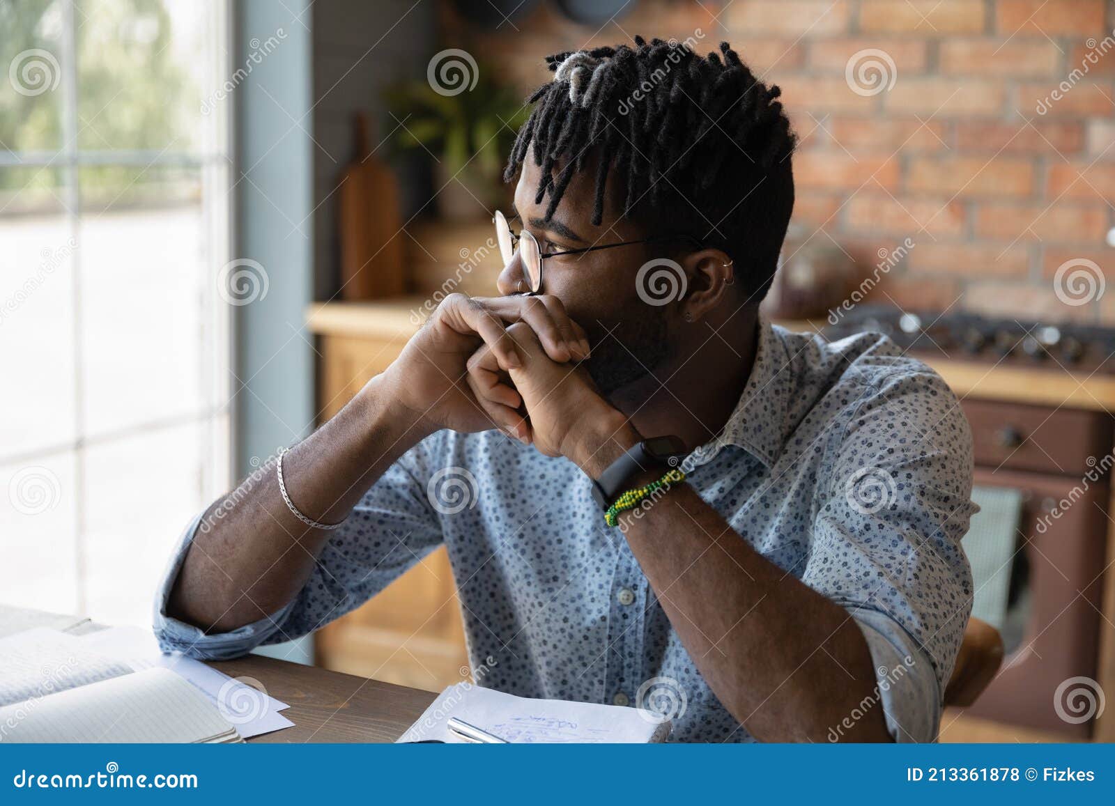 pensive african male student sit at table reflect on task