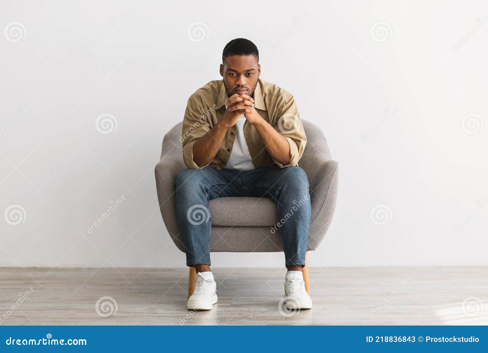 Thoughtful African Man Thinking Sitting in Chair Over Gray ...