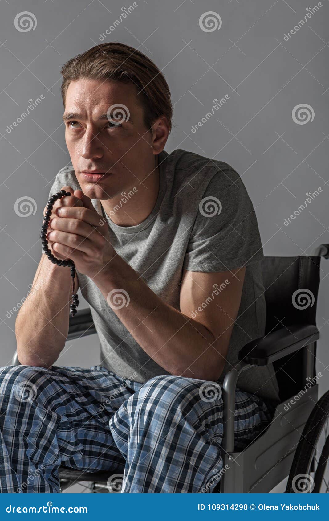 thoughtful invalid praying with beads in arms