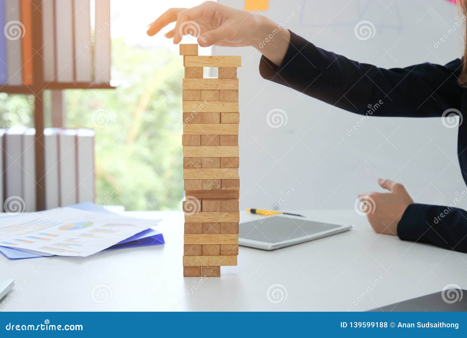 thoughtful and mindful business woman playing wooden block tower in office. risk and strategy business concept