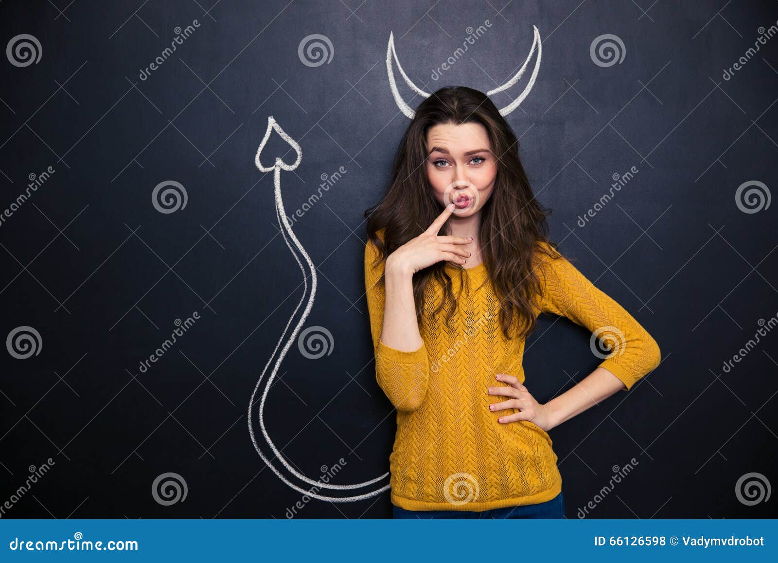 thoughtful playful young woman standing over chalkboard background drawn devils horns tail 66126598