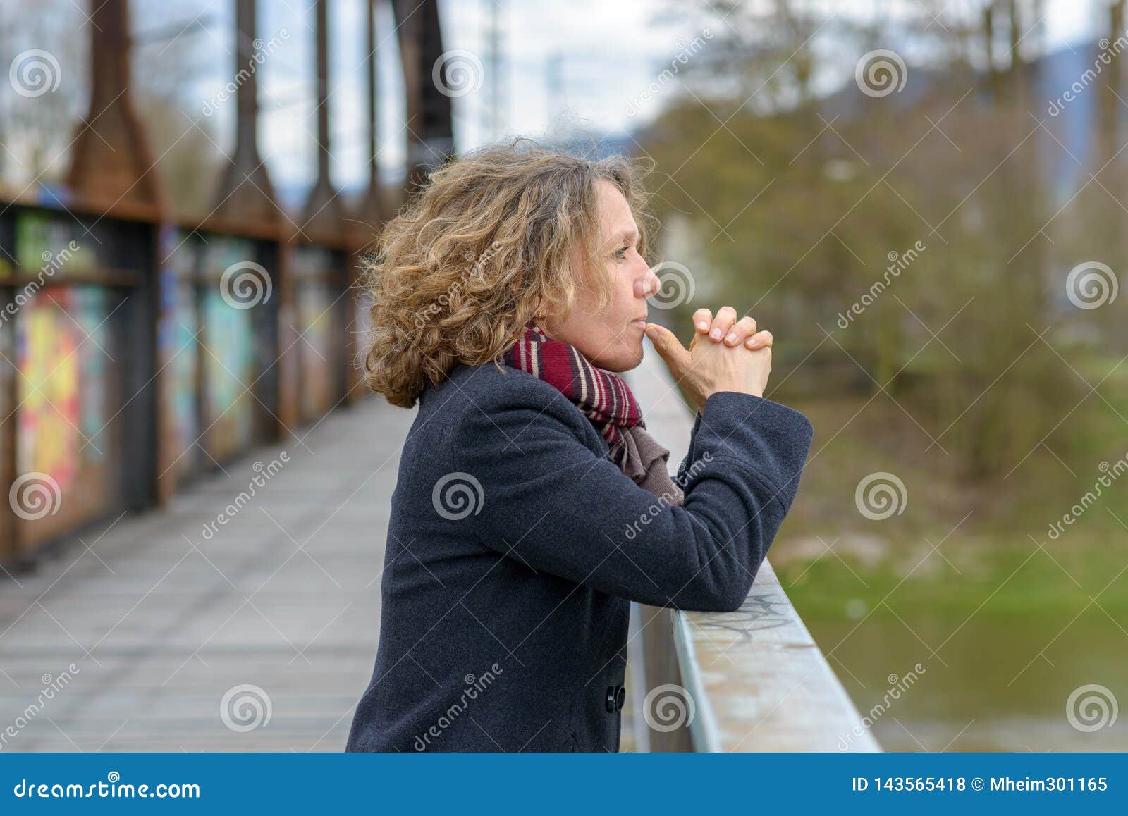 thoughtful woman gazing out from a bridge