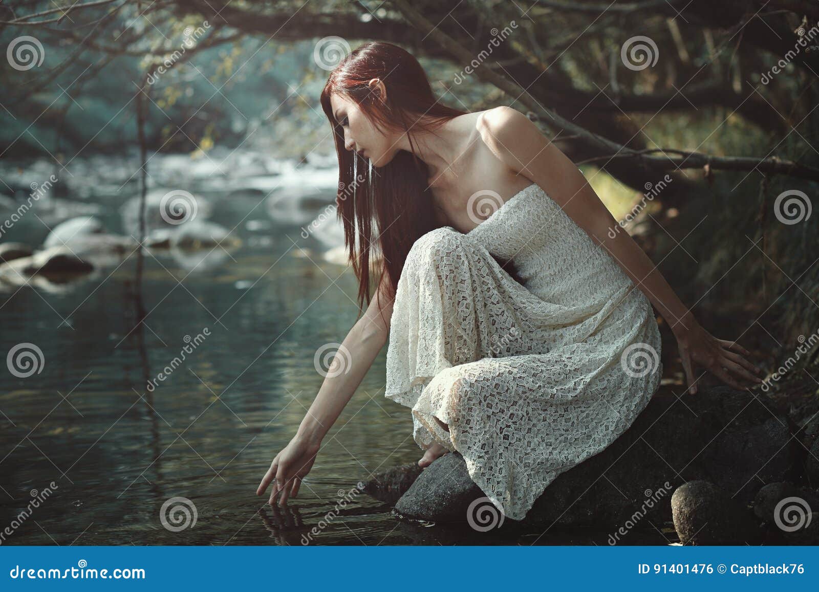 thoughtful woman touching stream waters