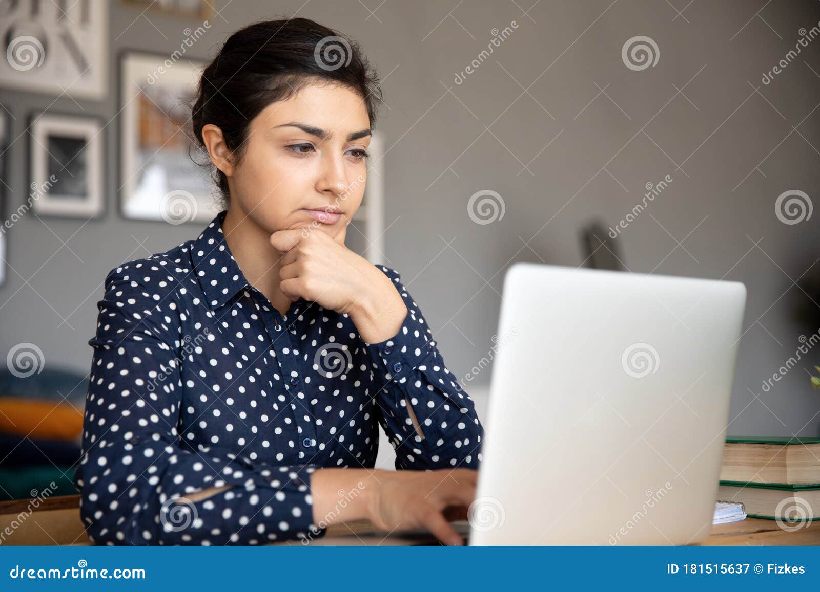 thoughtful young indian woman looking at computer screen.