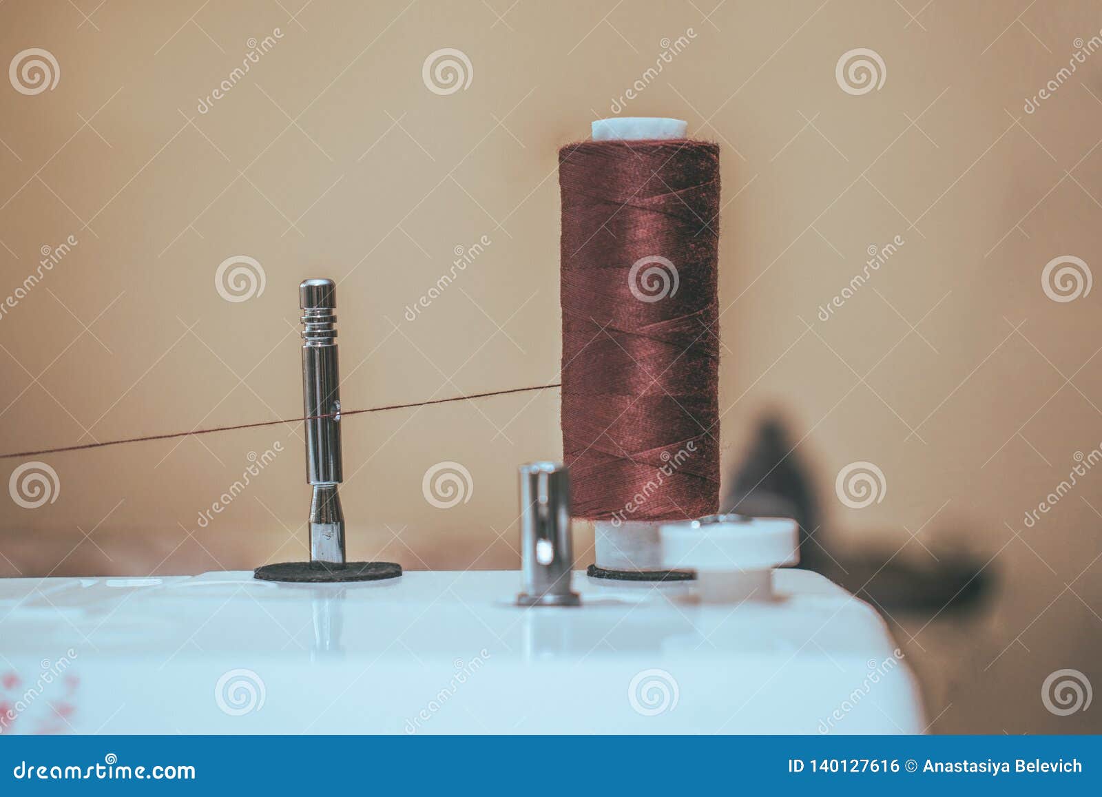 Thread Spool on a Sewing Machine Closeup on the Brown Backgound Stock