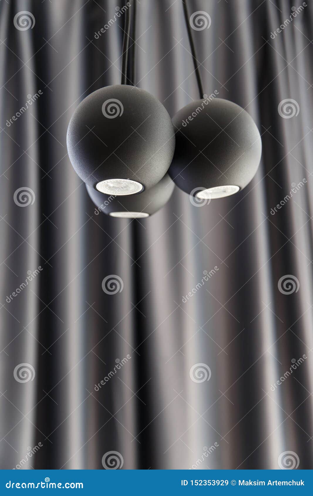three ball d led illuminators are hanging from the ceiling. black curtain on the backround