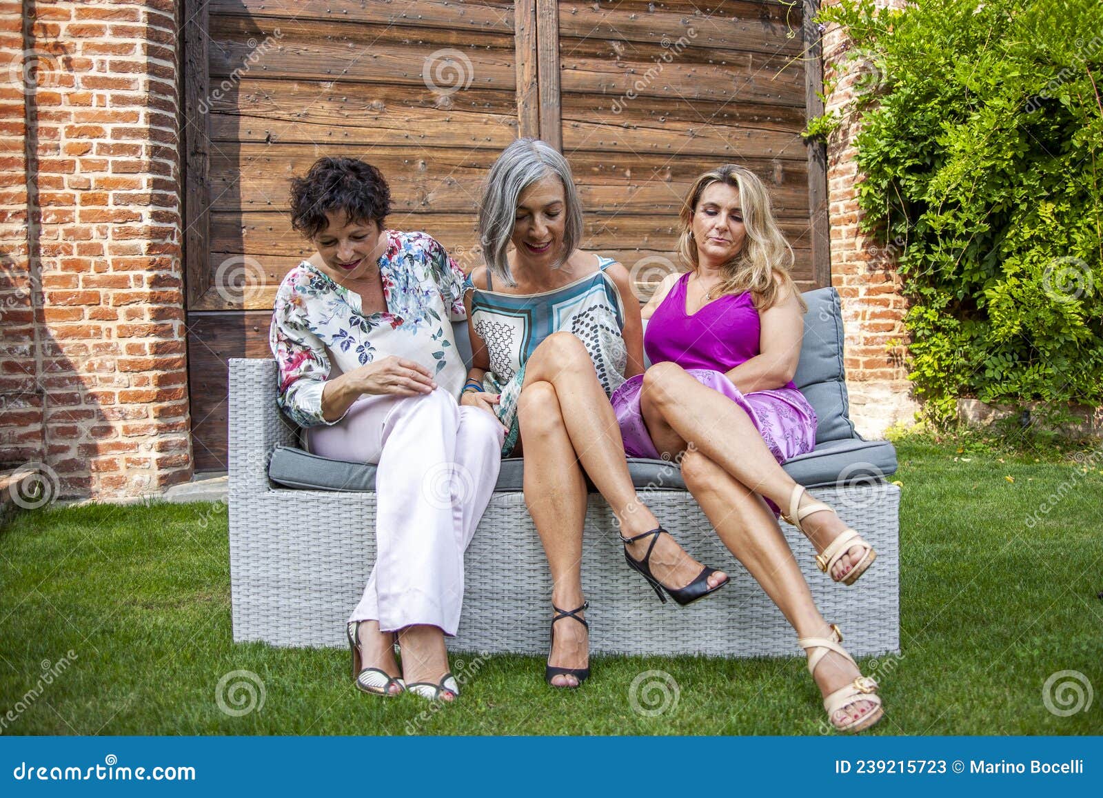 Three Beautiful Middle Aged Women Are Relaxing In Their Free Time Sitting On An Bench Stock
