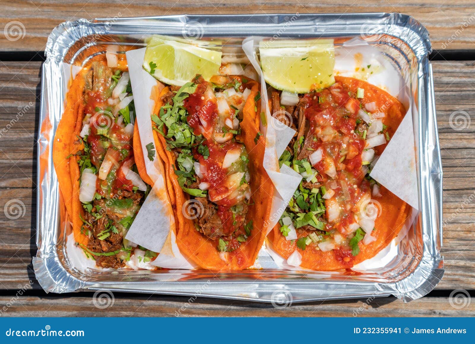 Three Birria Tacos with Limes in a Takeout Container Stock Image