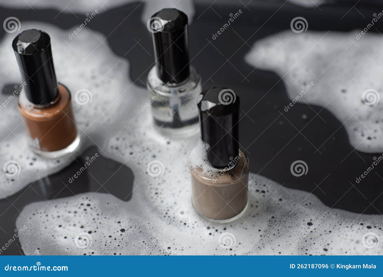 The Three Bottles of Nail Polish Sit on a Wet Black Floor. Stock Photo
