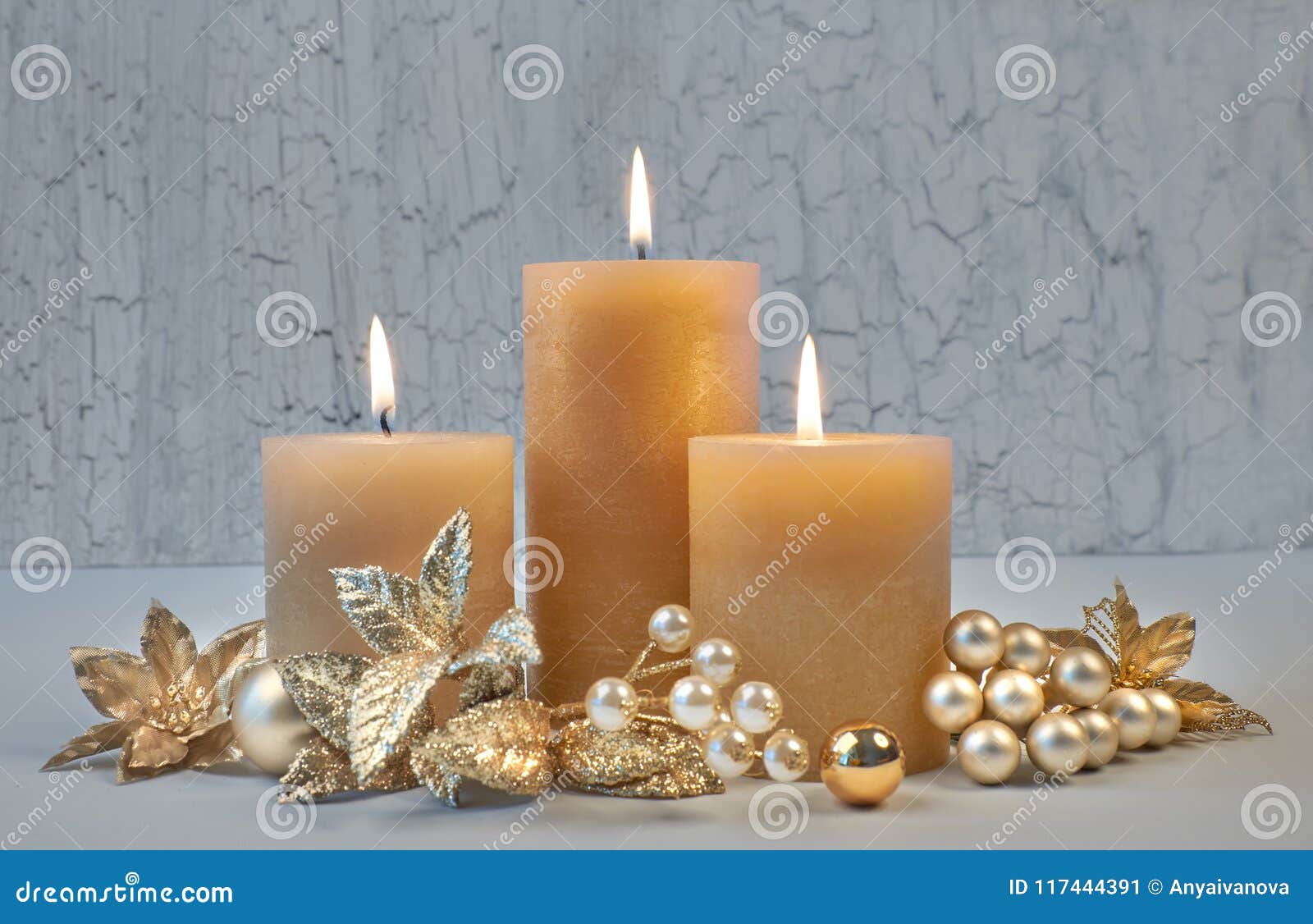 Three Burning Candles with Golden Christmas Decorations on Rusti Stock